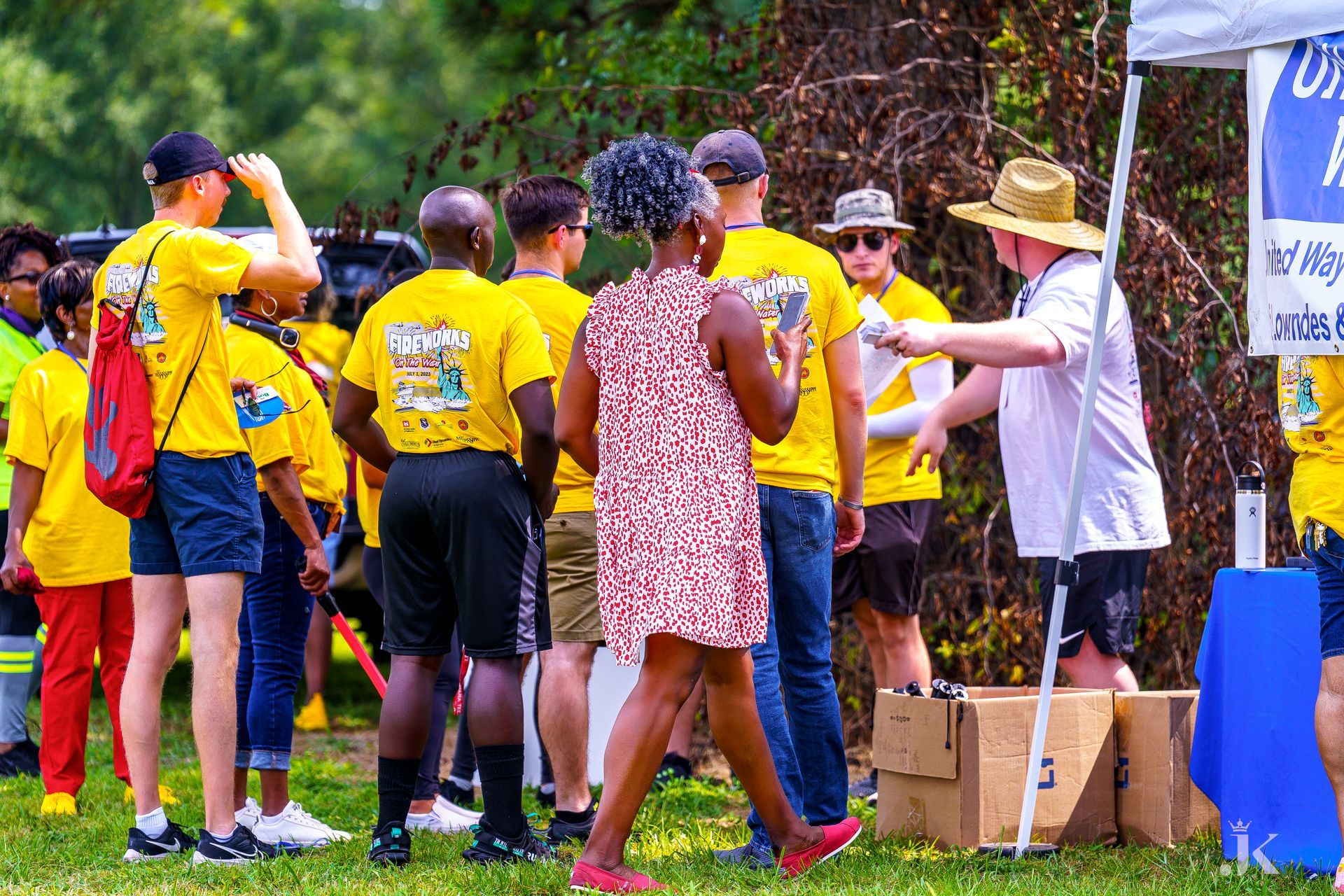 A group of people are standing around a table in a park.