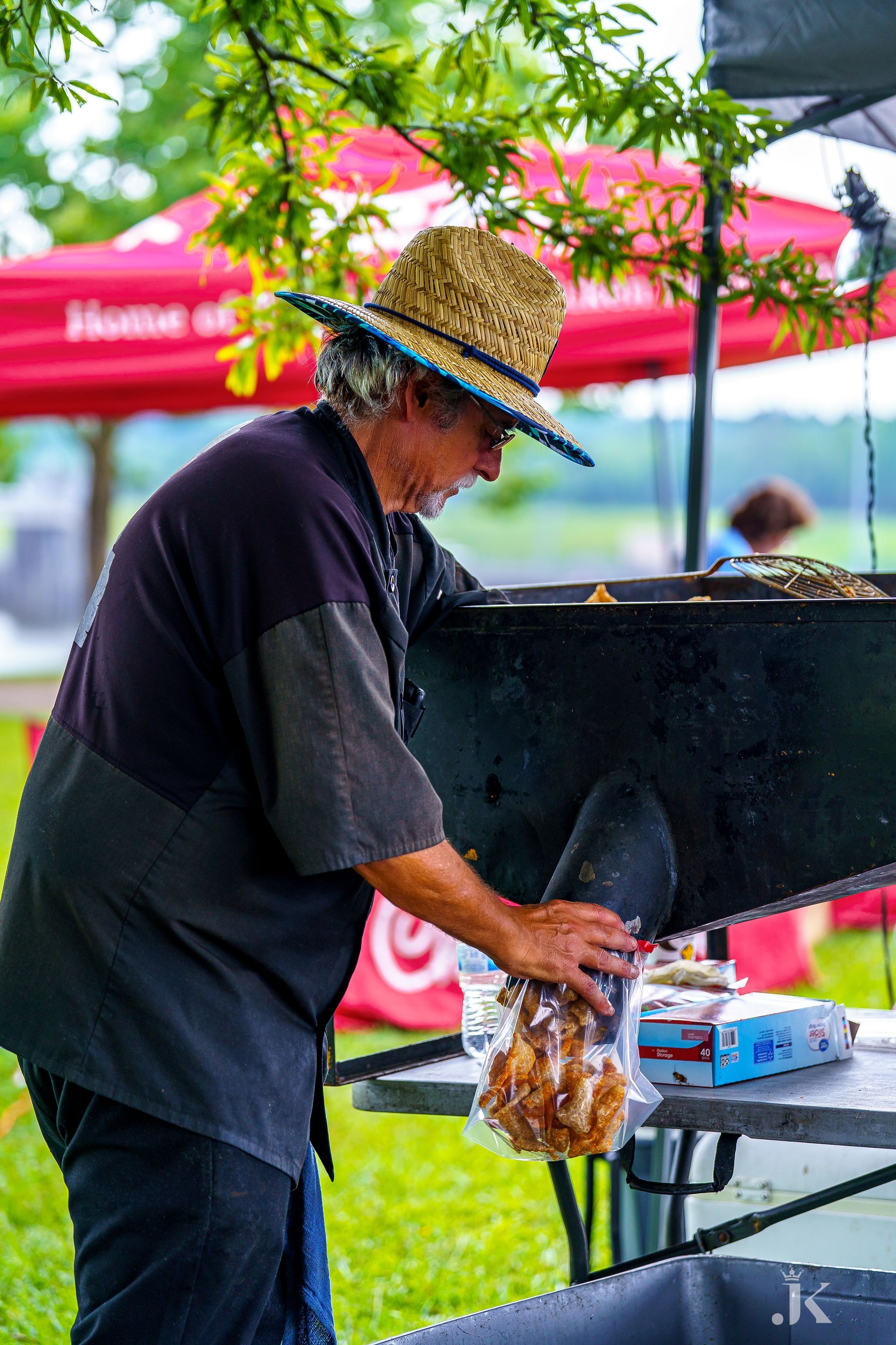 A man in a straw hat is cooking food on a grill.