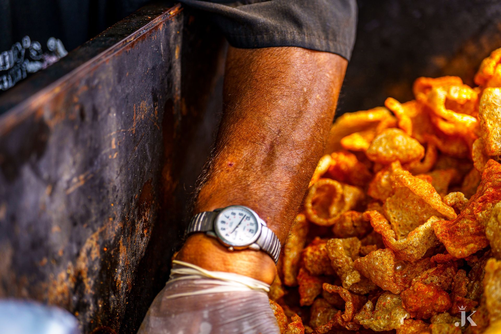 A person wearing a watch is standing next to a pile of food.