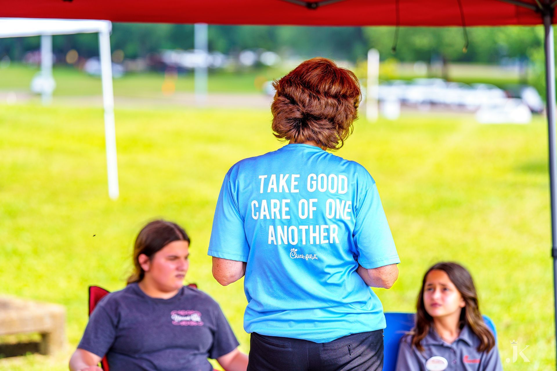A woman is wearing a blue shirt that says `` take good care of one another ''.