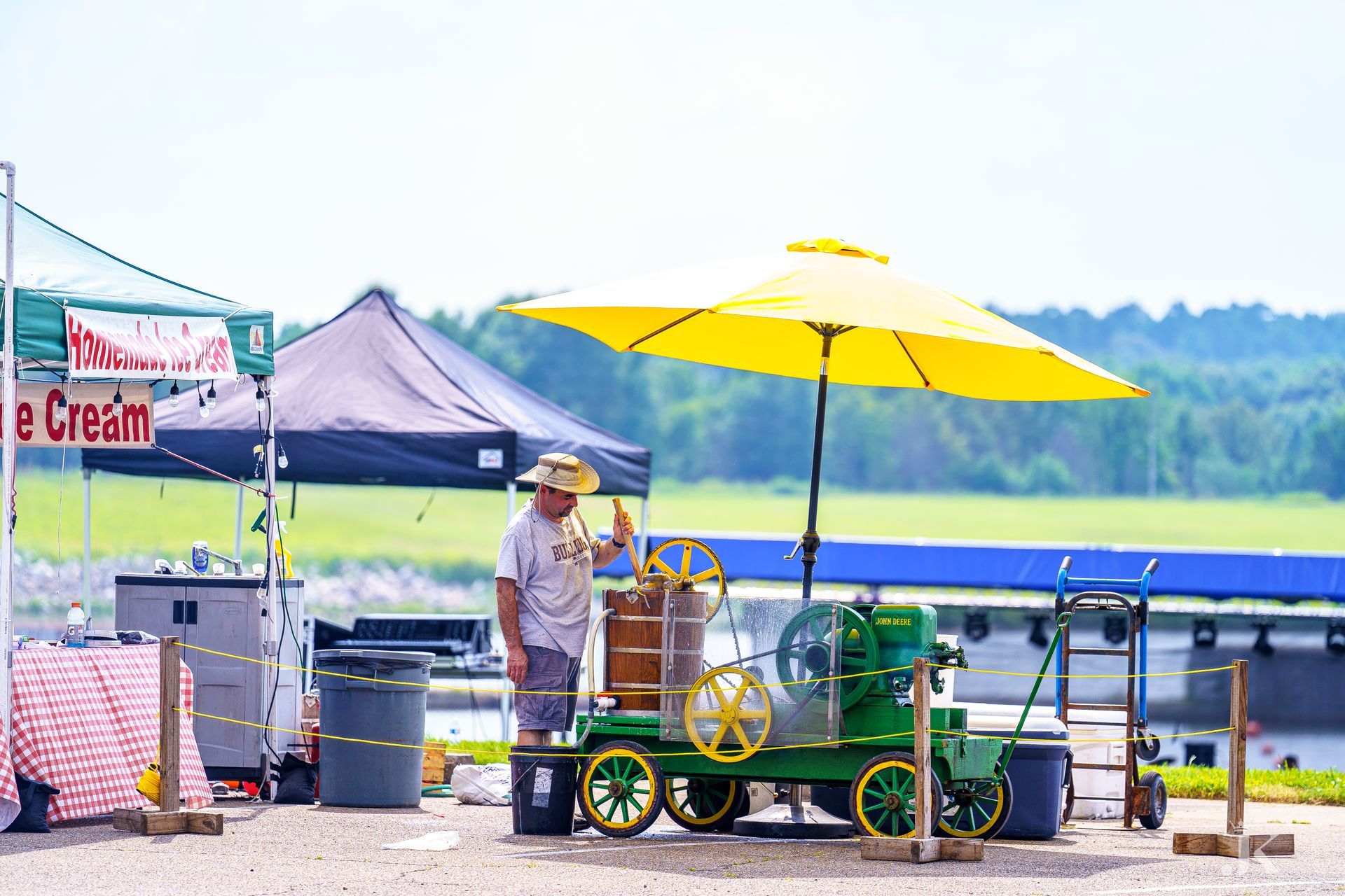 A man is standing next to an ice cream cart with a yellow umbrella.