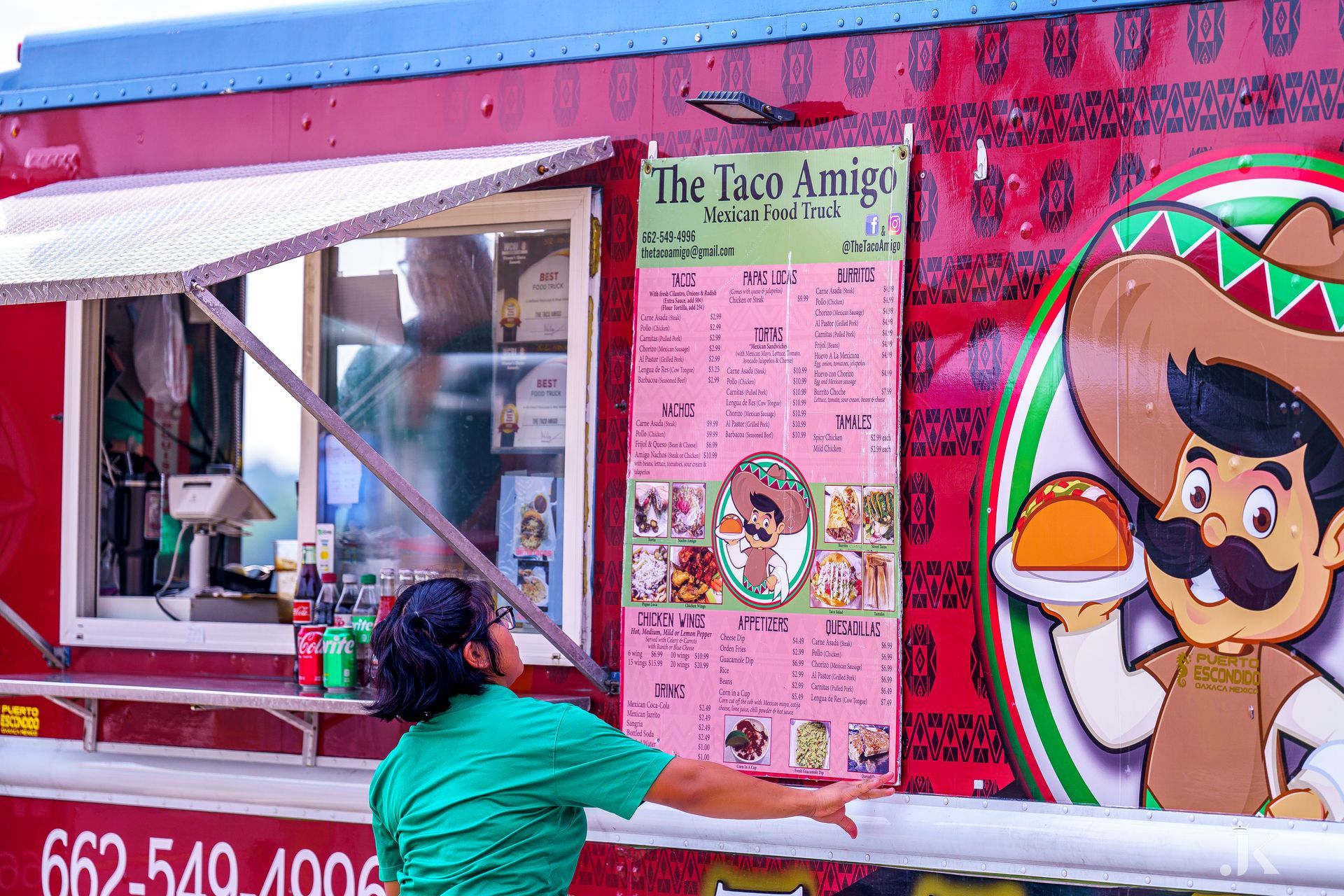 A man is standing in front of a taco truck.