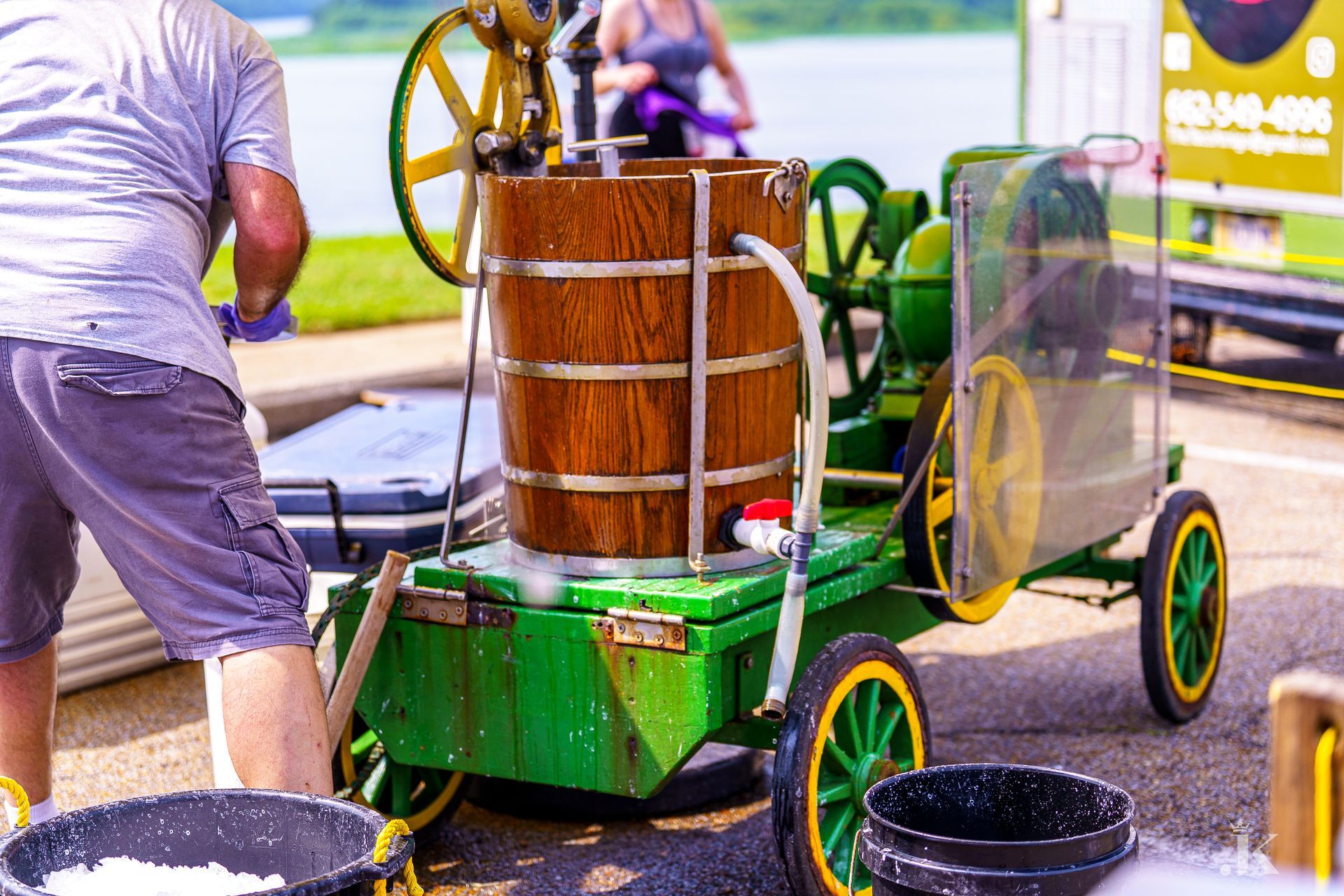 A man is standing next to a cart with a wooden bucket on it.