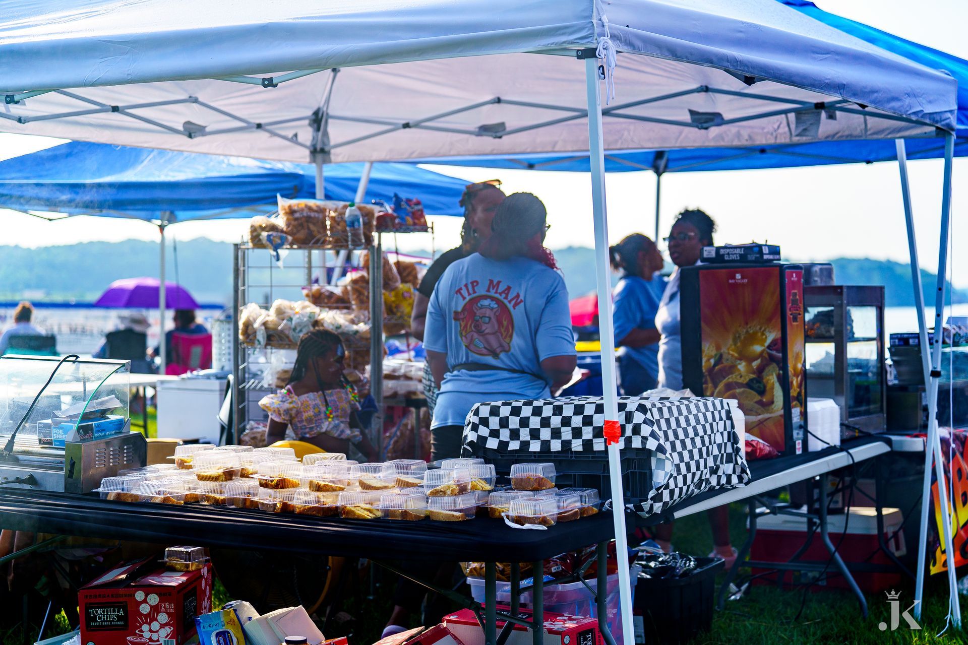 A group of people are working at a food stand under a tent.