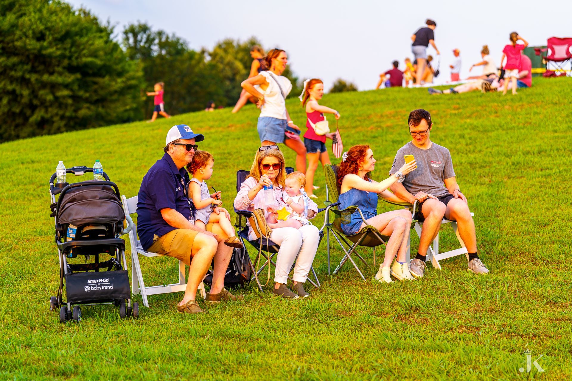 A group of people are sitting in chairs in a grassy field.