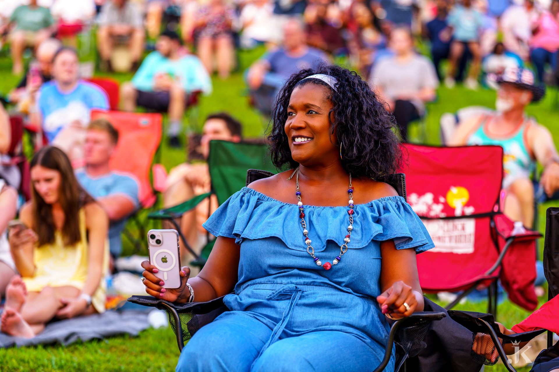 A woman is sitting in a chair holding a cell phone.