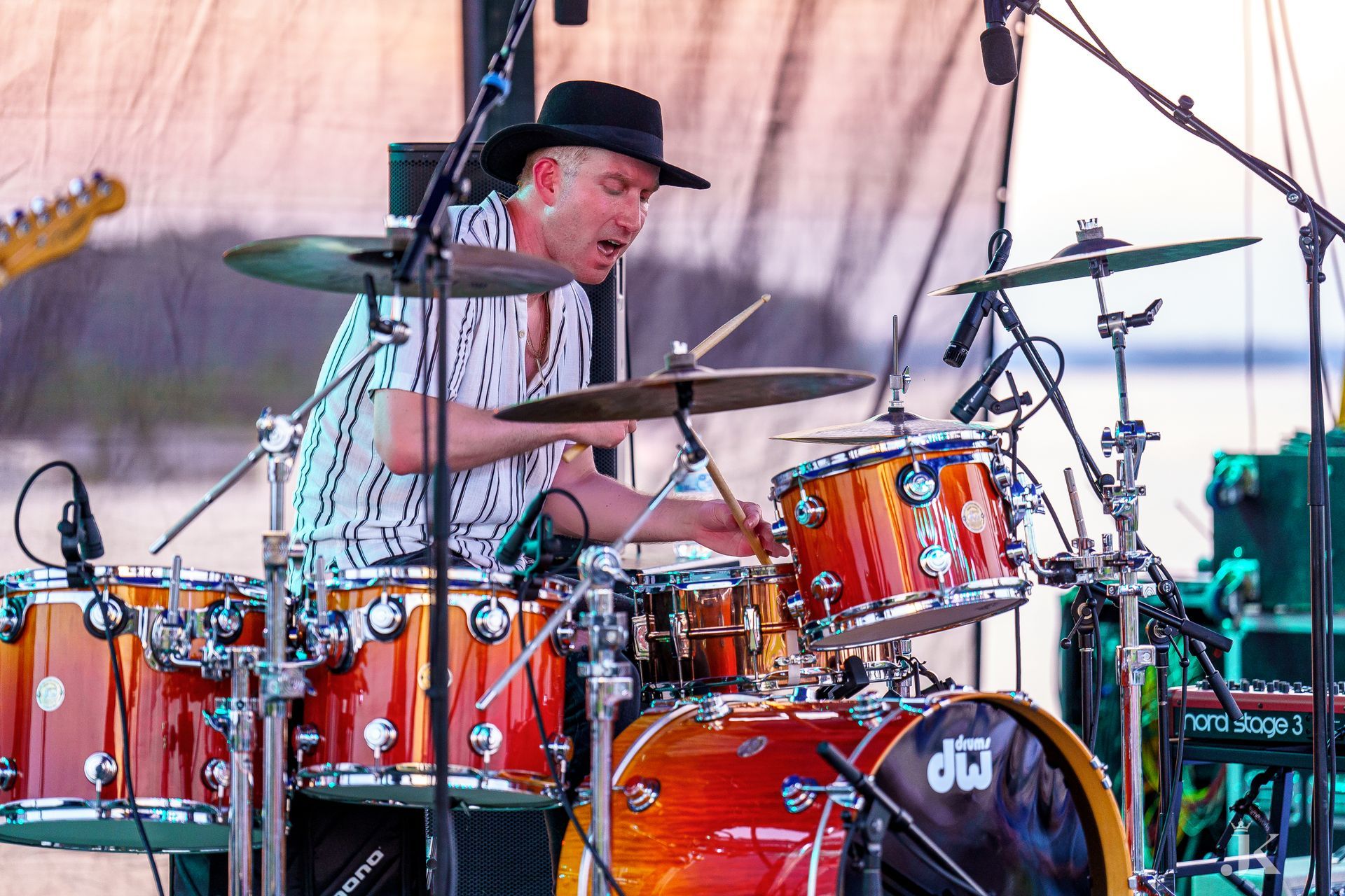A man in a hat is playing drums on a stage.