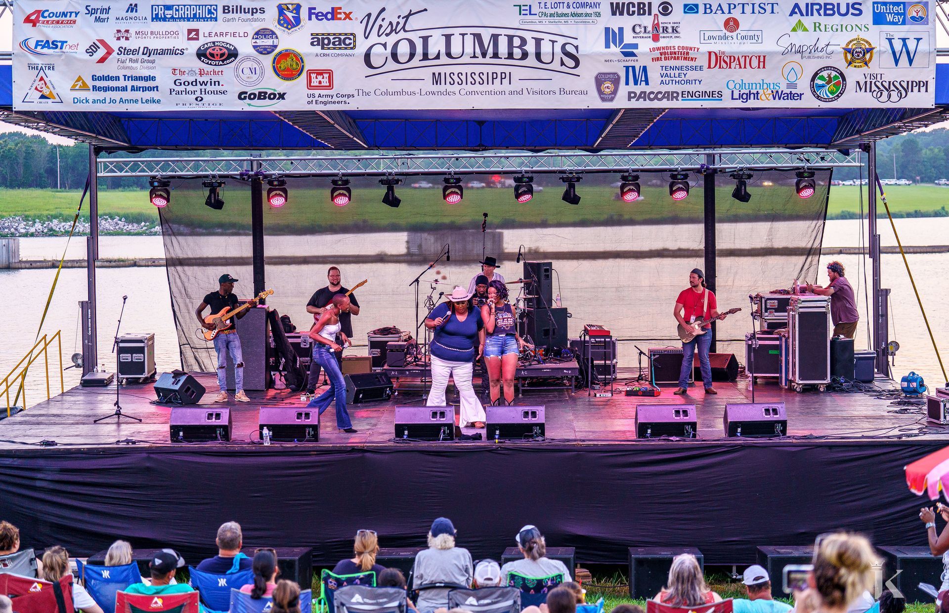 A group of people are sitting in front of a stage with a sign that says columbus on it.