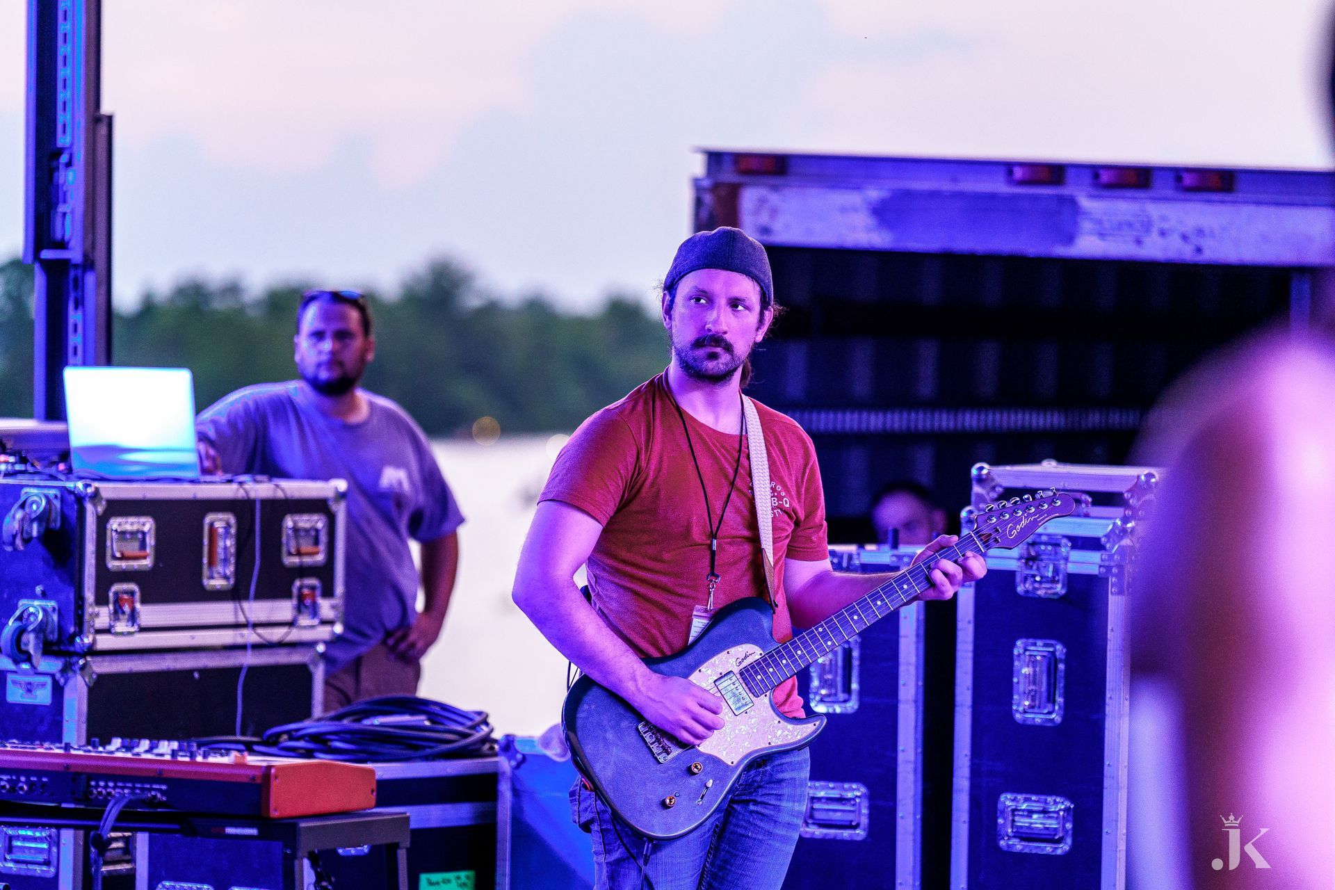 A man is playing a guitar on stage while a man stands behind him.