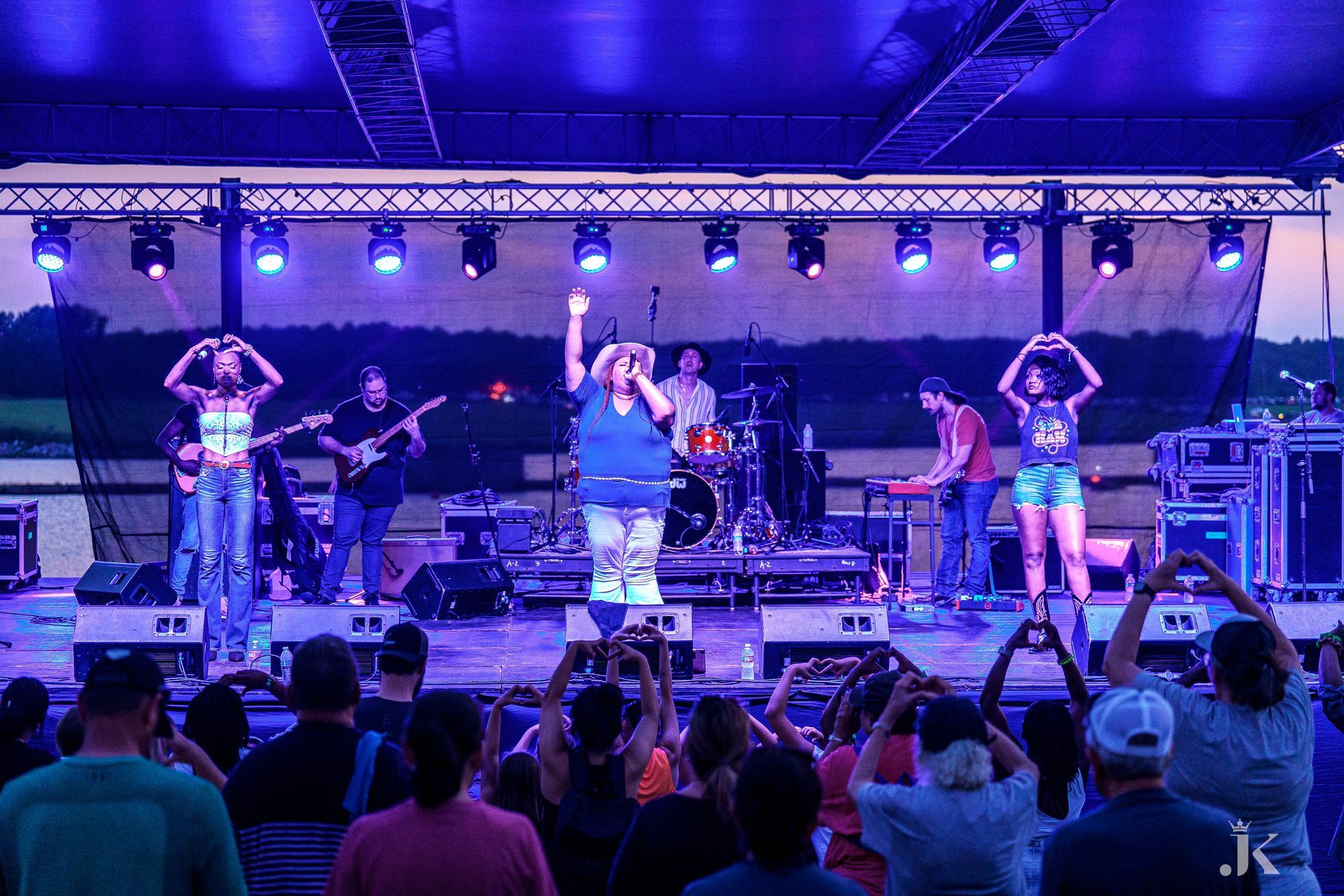 A group of people are standing in front of a stage at a concert.