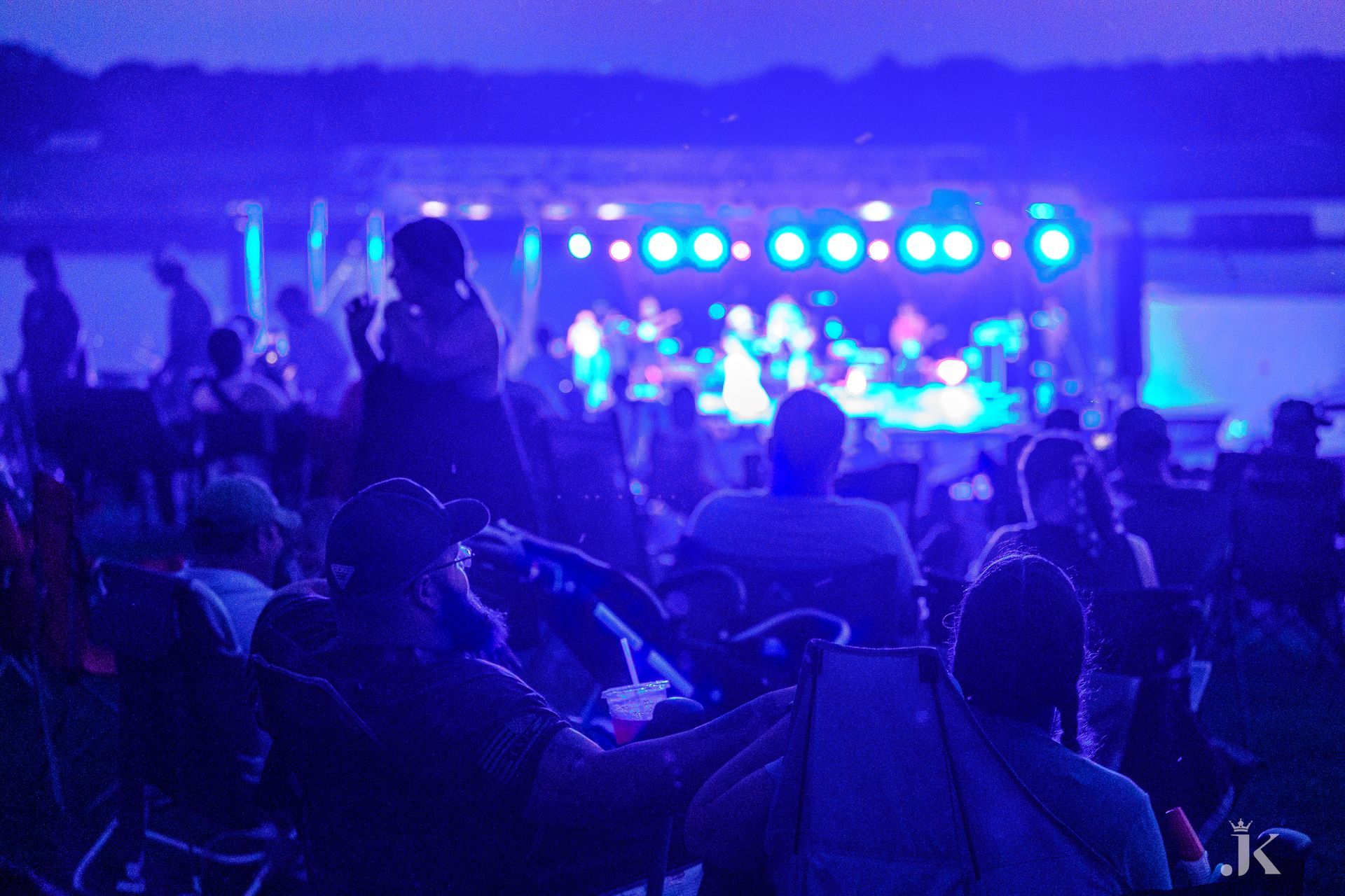 A crowd of people are sitting in front of a stage at a concert.