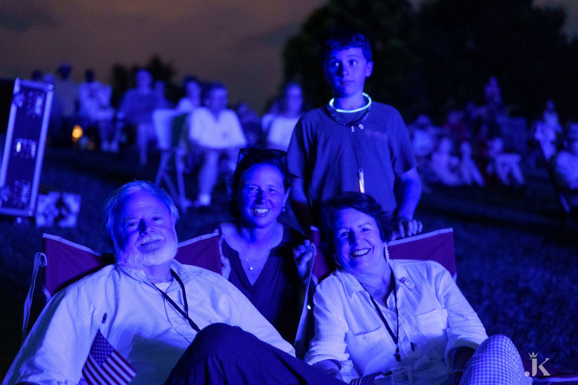 A group of people are sitting in chairs watching a fireworks display.