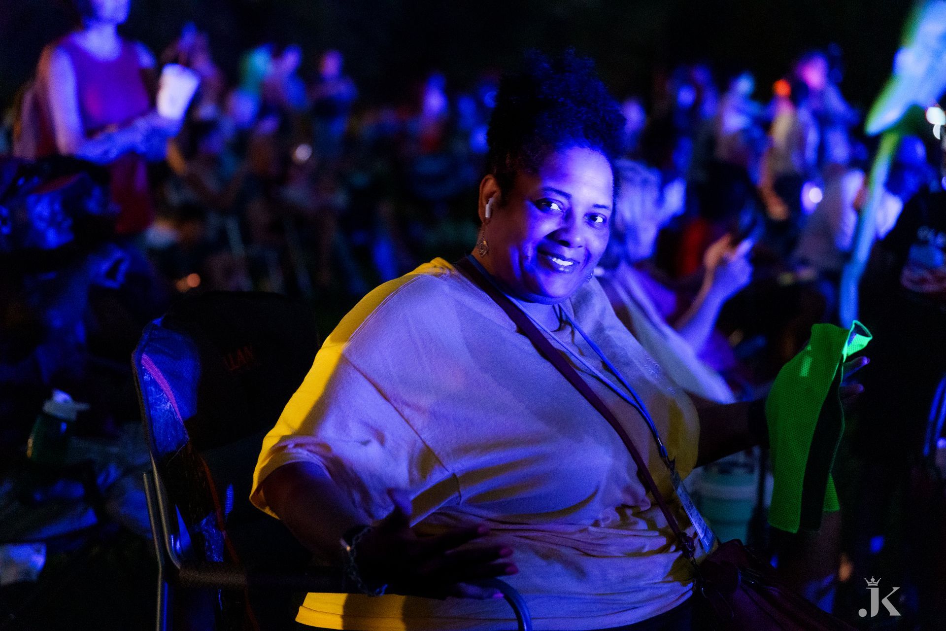 A woman is smiling in front of a crowd at a concert.
