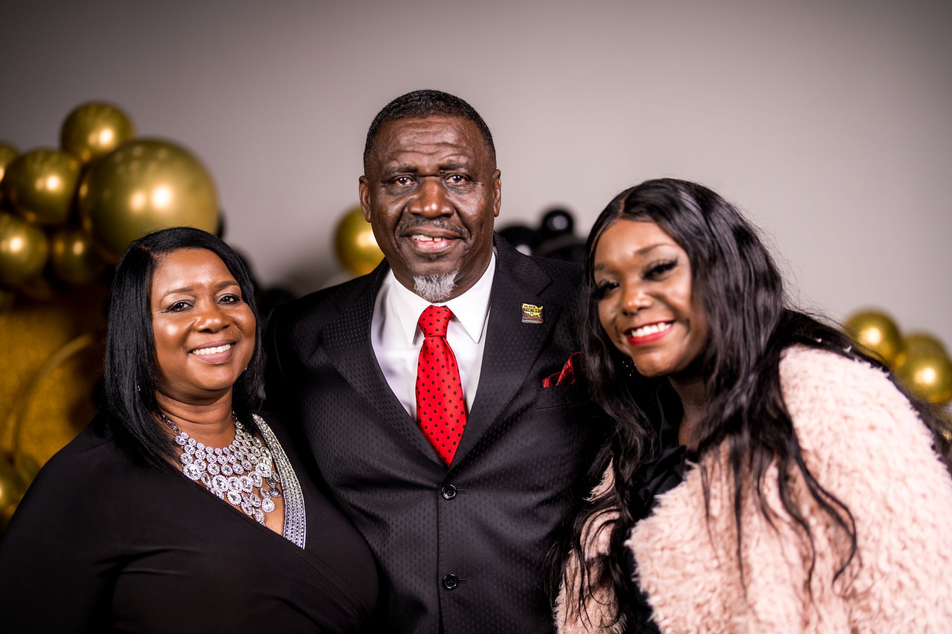 A man in a suit and tie is posing for a picture with two women.