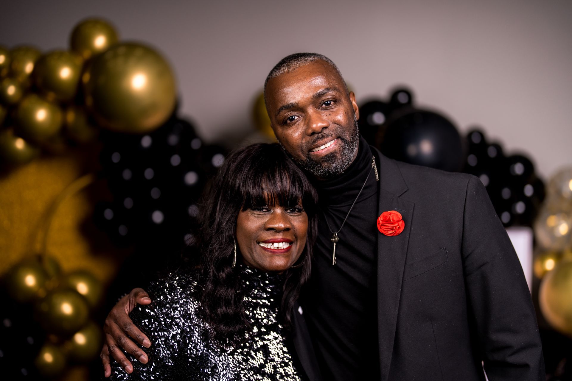 A man and a woman are posing for a picture in front of balloons.