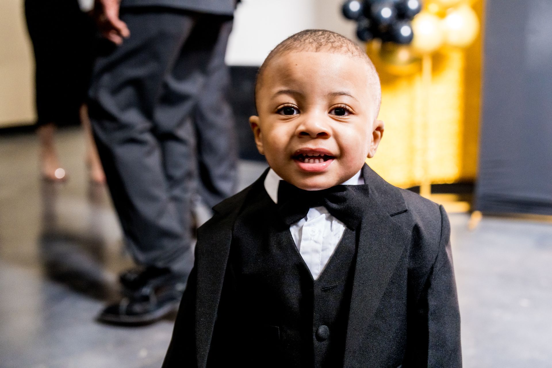 A little boy is wearing a tuxedo and bow tie.