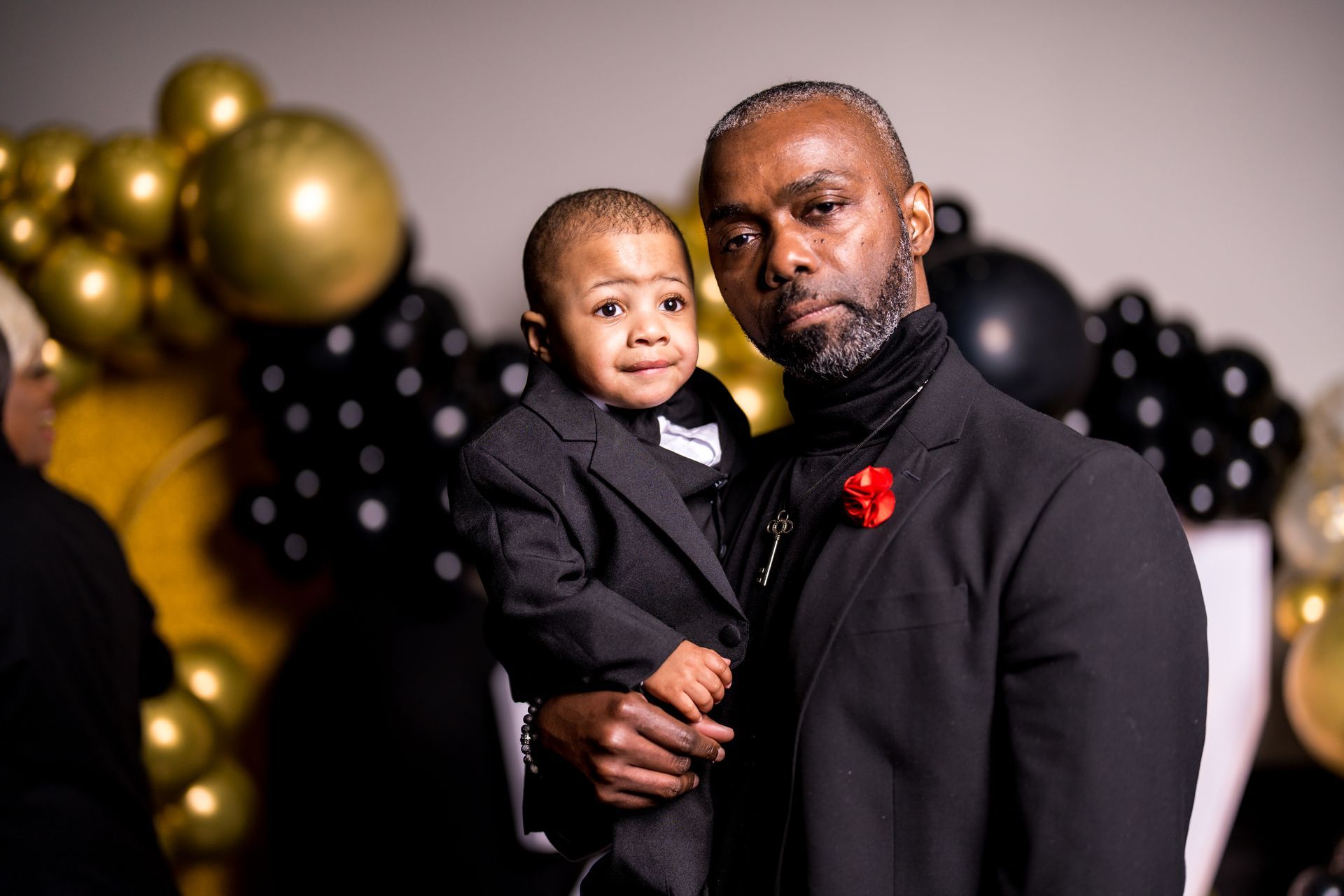 A man in a suit is holding a little boy in his arms.