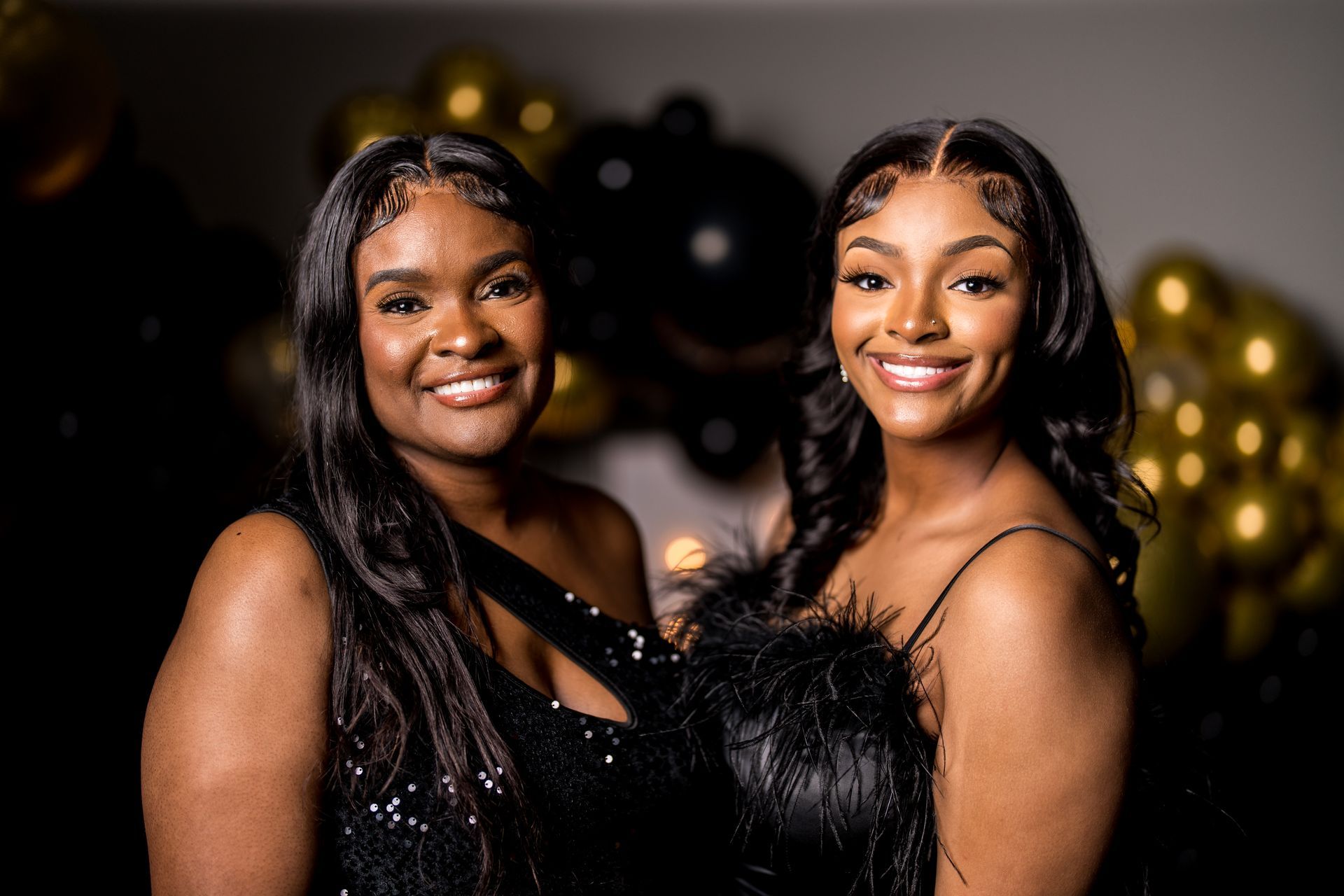 Two women are posing for a picture together in front of balloons.