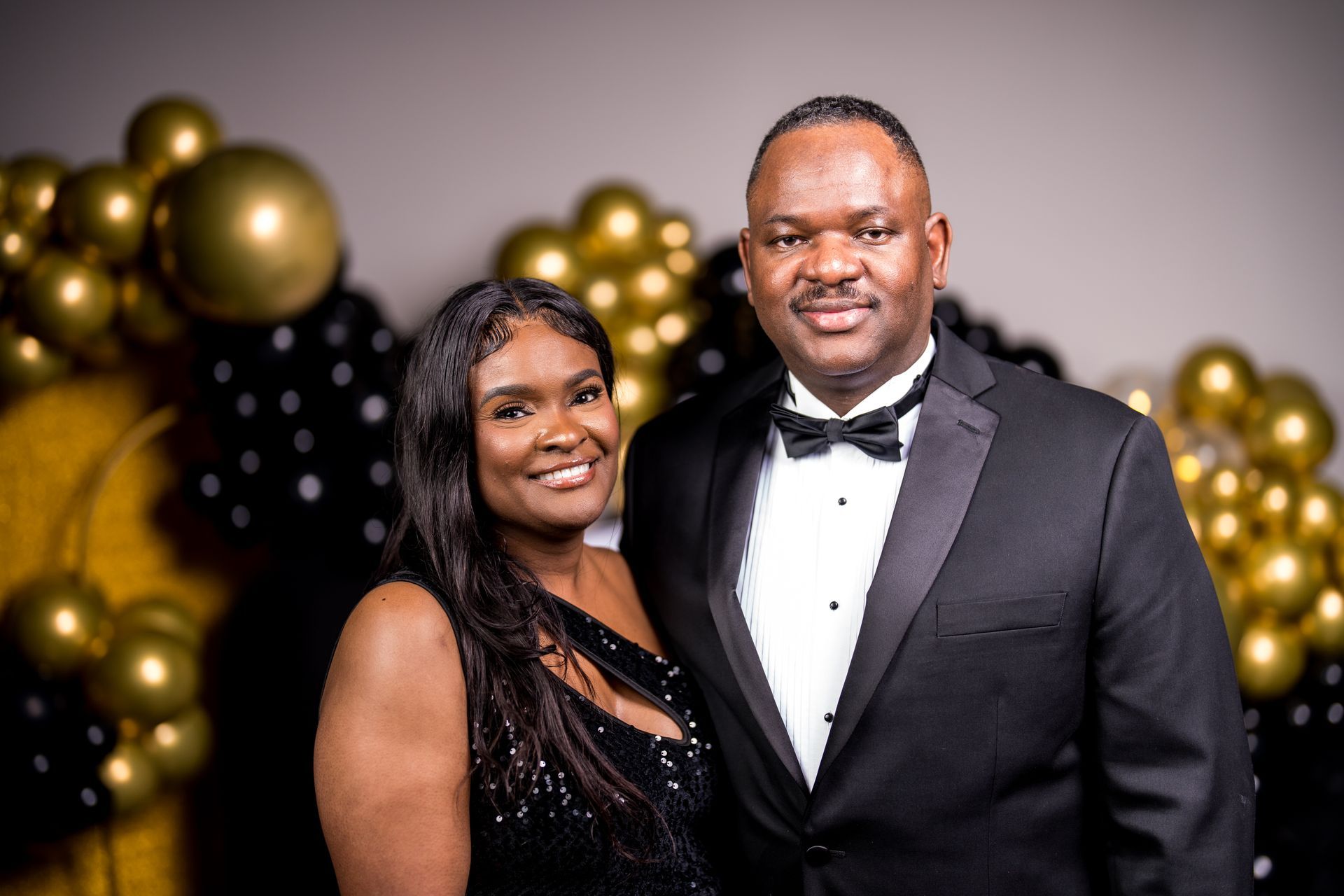 A man and a woman are posing for a picture in front of balloons.