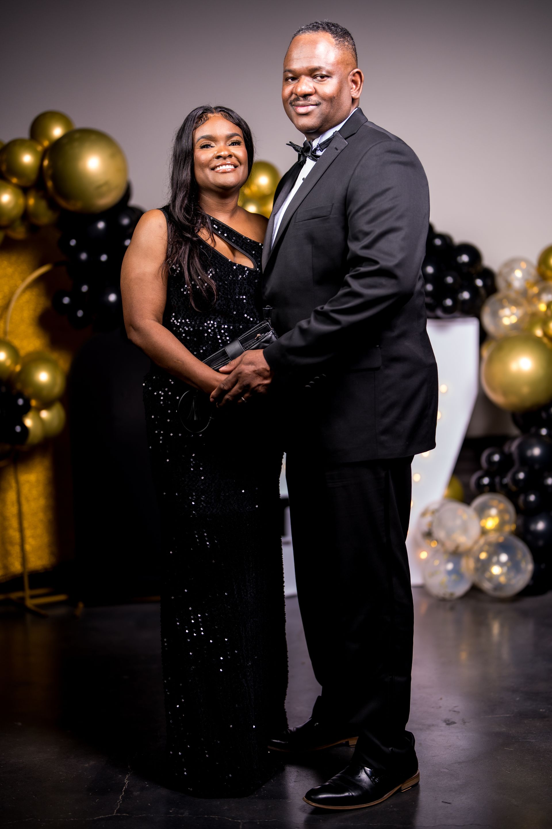 A man and a woman are standing next to each other in front of balloons.
