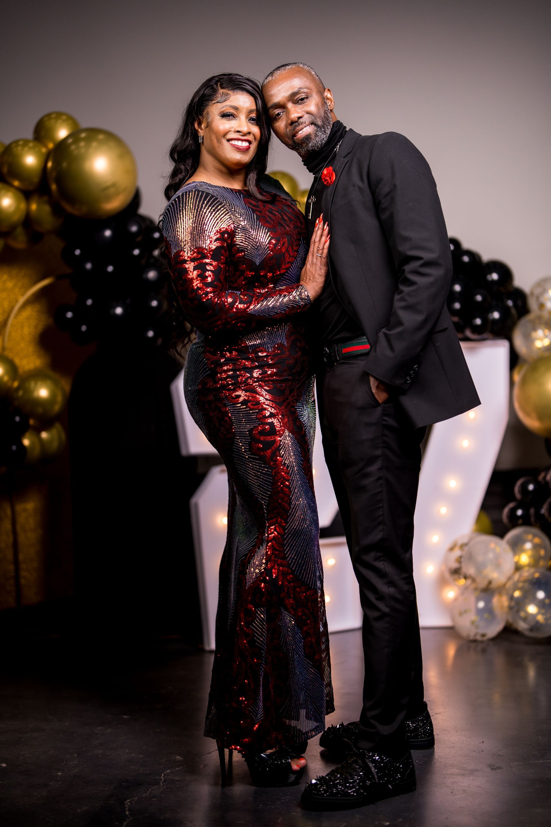 A man and a woman are posing for a picture in front of balloons.
