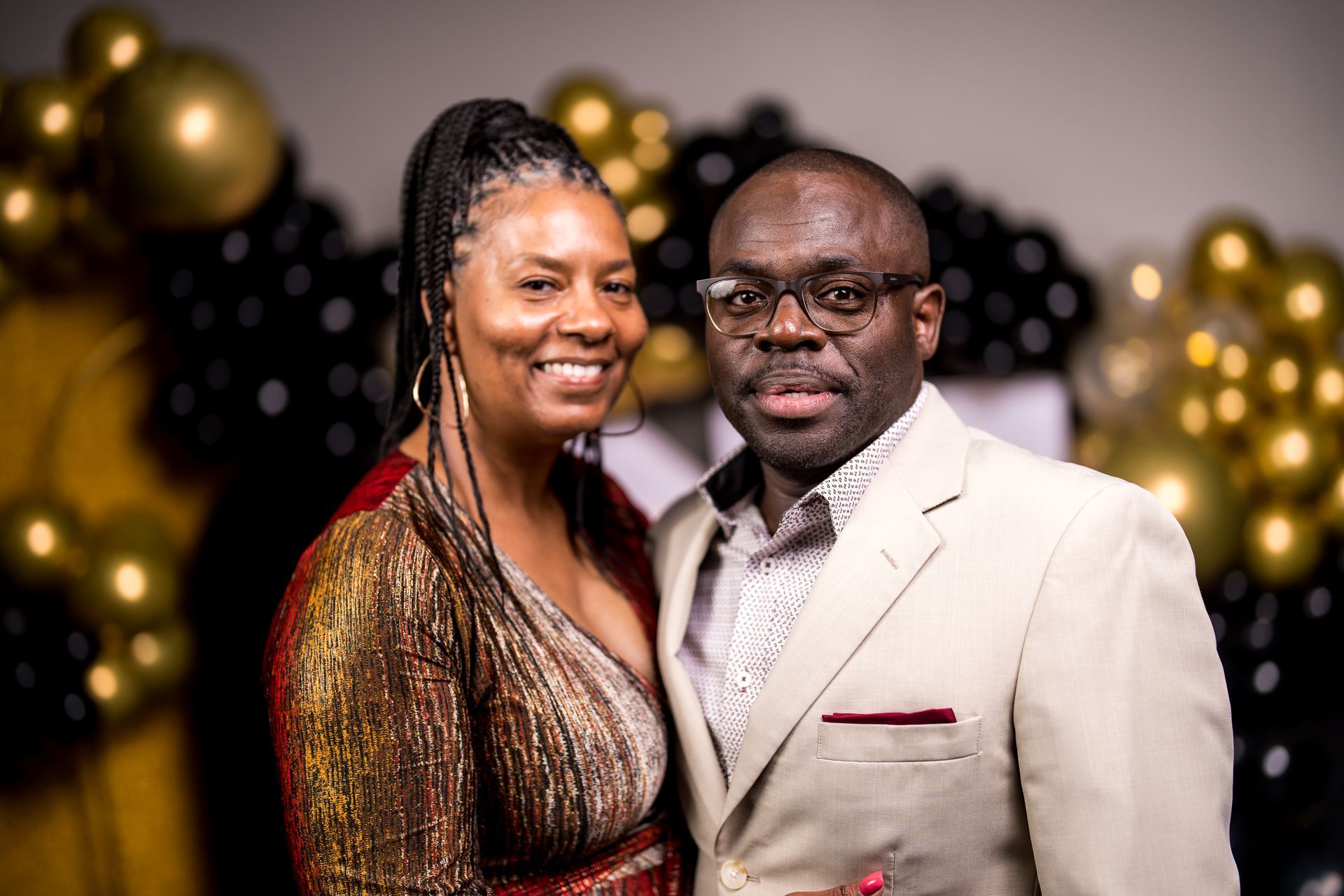 A man and a woman are posing for a picture in front of balloons.