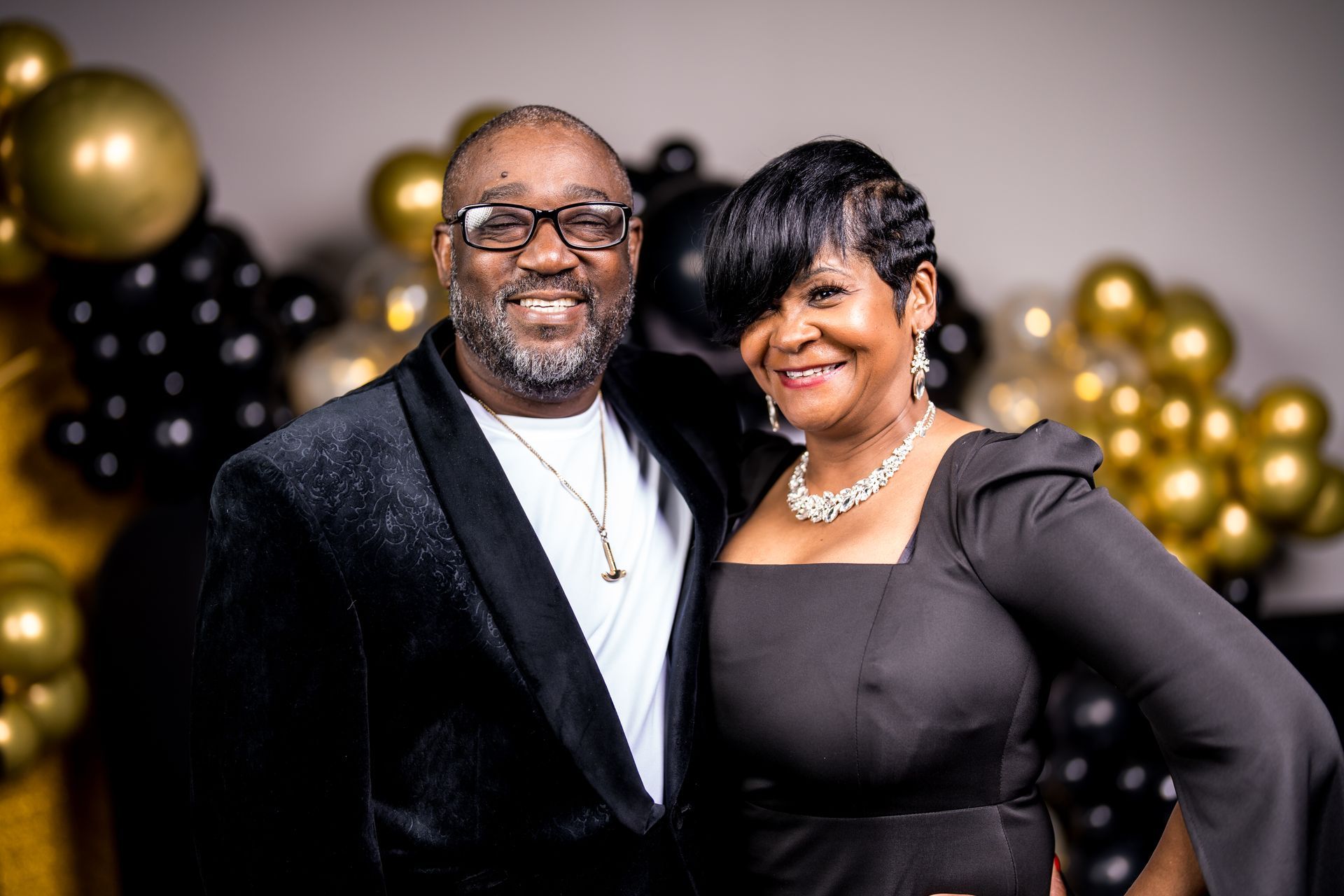 A man and a woman are posing for a picture in front of balloons.