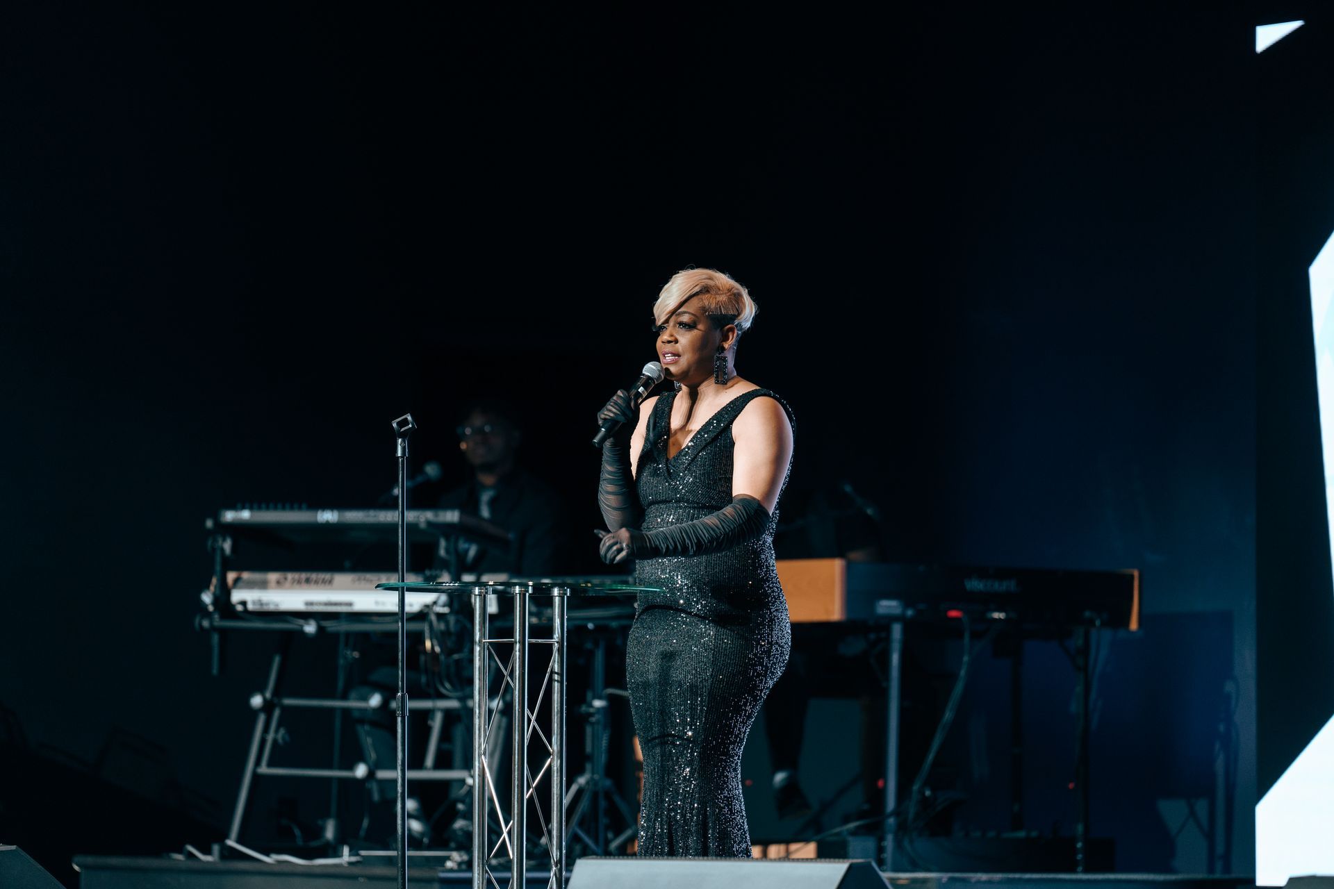 A woman is singing into a microphone on a stage.