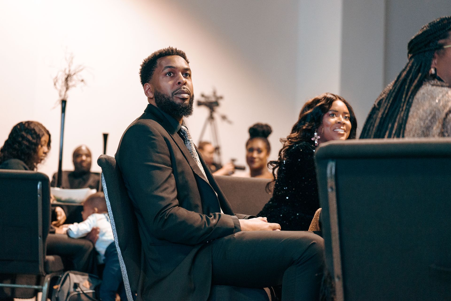 A man in a suit and tie is sitting in a church with other people.