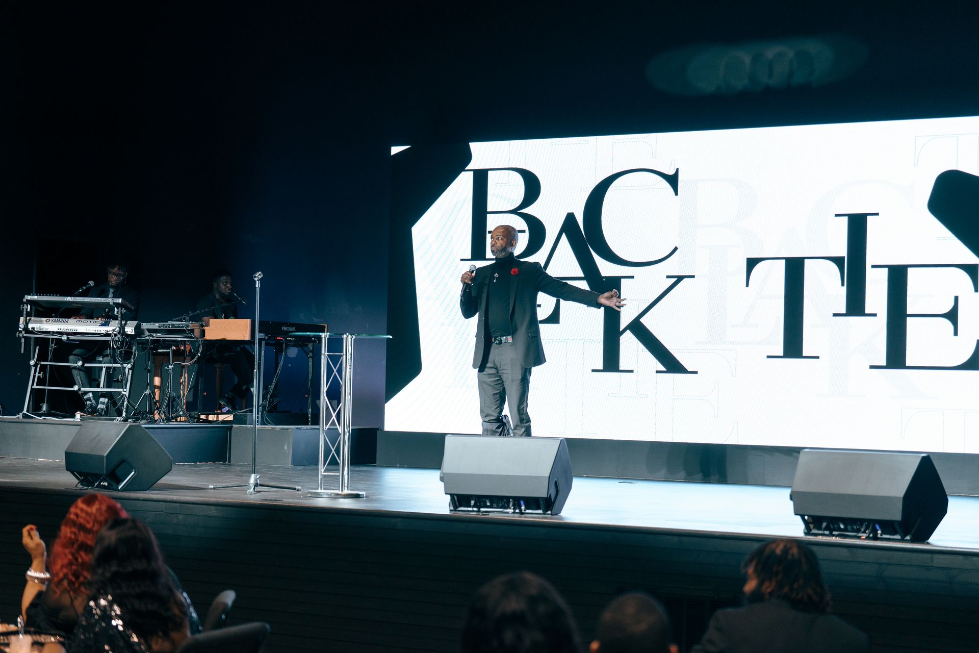 A man is standing on a stage in front of a large screen.