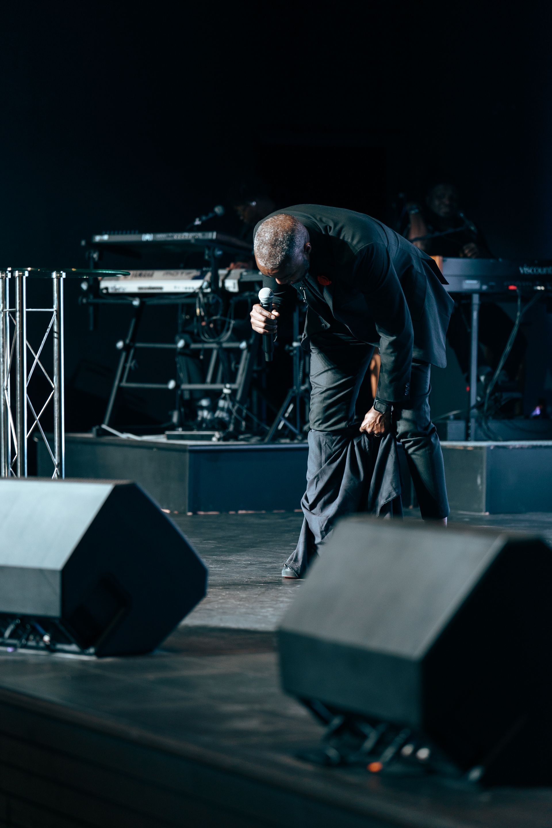 A man is kneeling down on a stage holding a microphone.