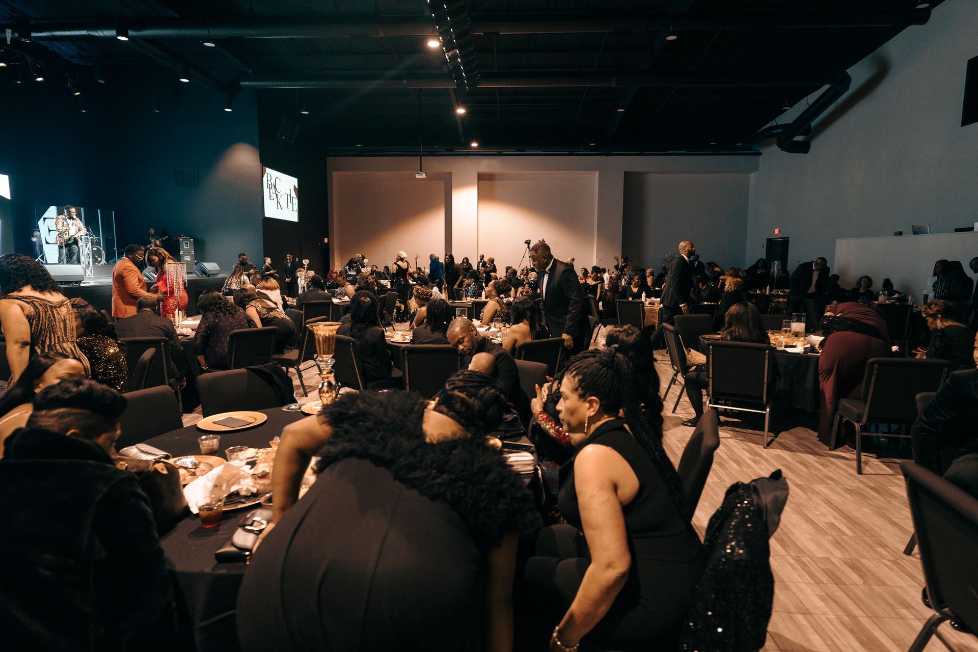 A large group of people are sitting at tables in a large room.