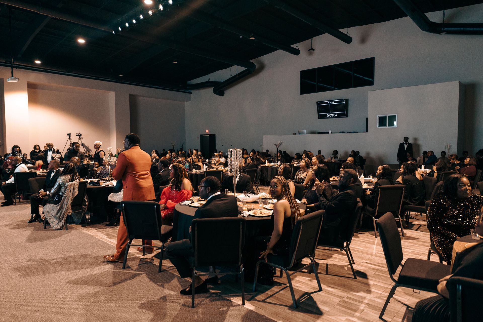 A large group of people are sitting at tables in a large room.