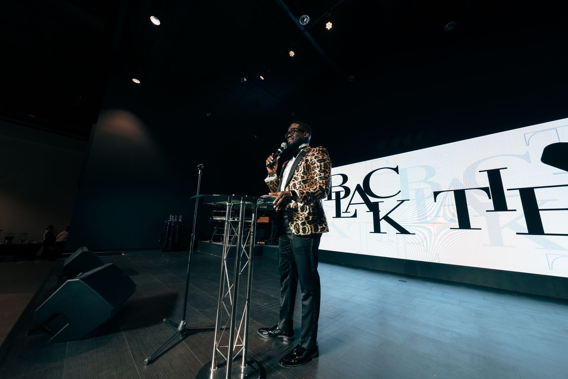 A man is standing at a podium on a stage holding a microphone.