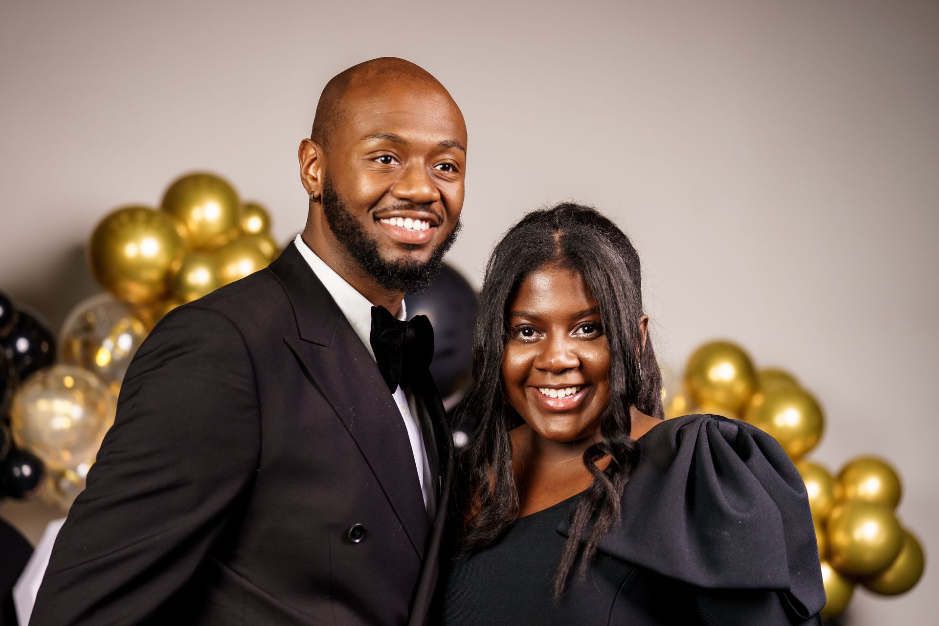 A man and a woman are posing for a picture in front of balloons.