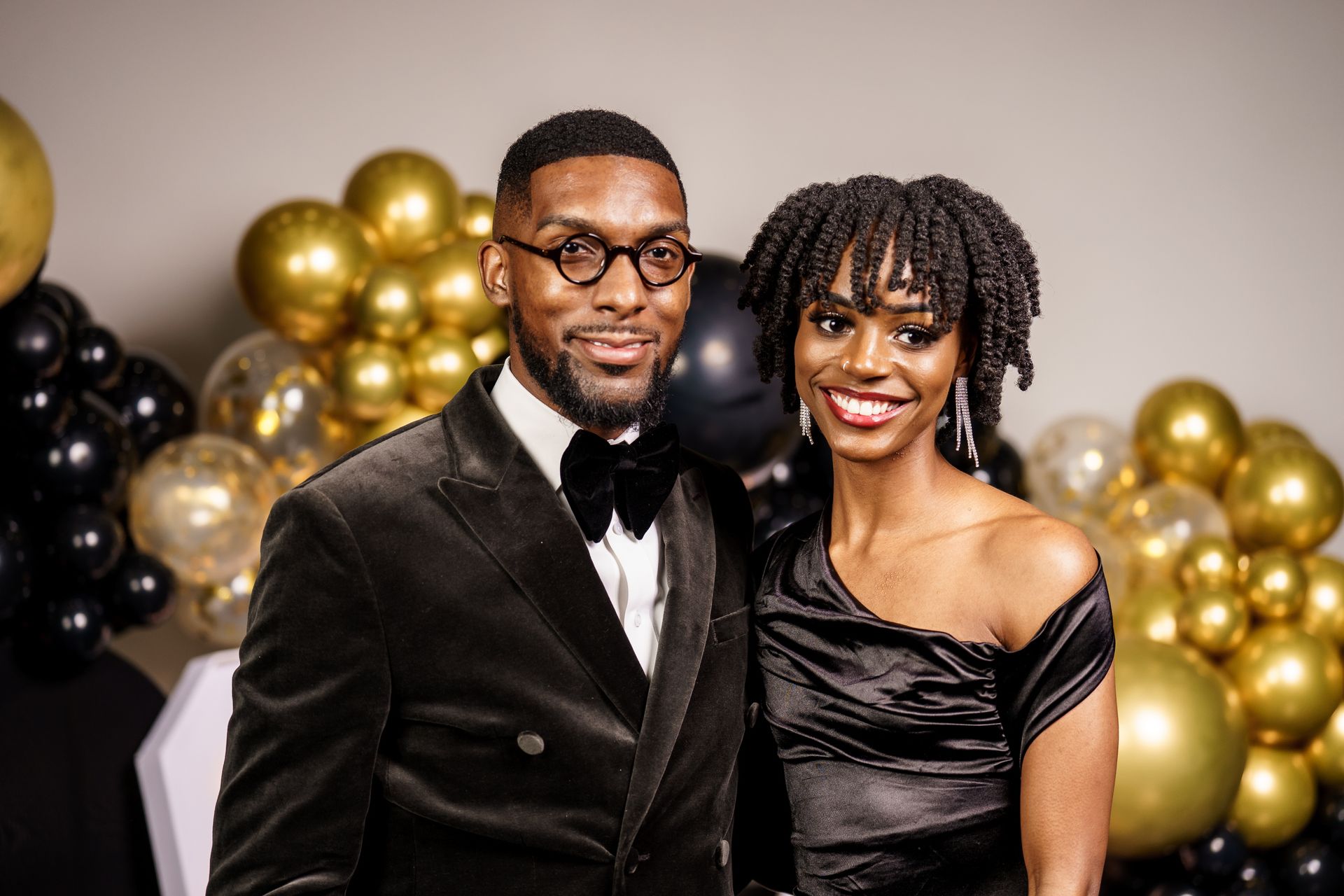 A man and a woman are posing for a picture in front of balloons.