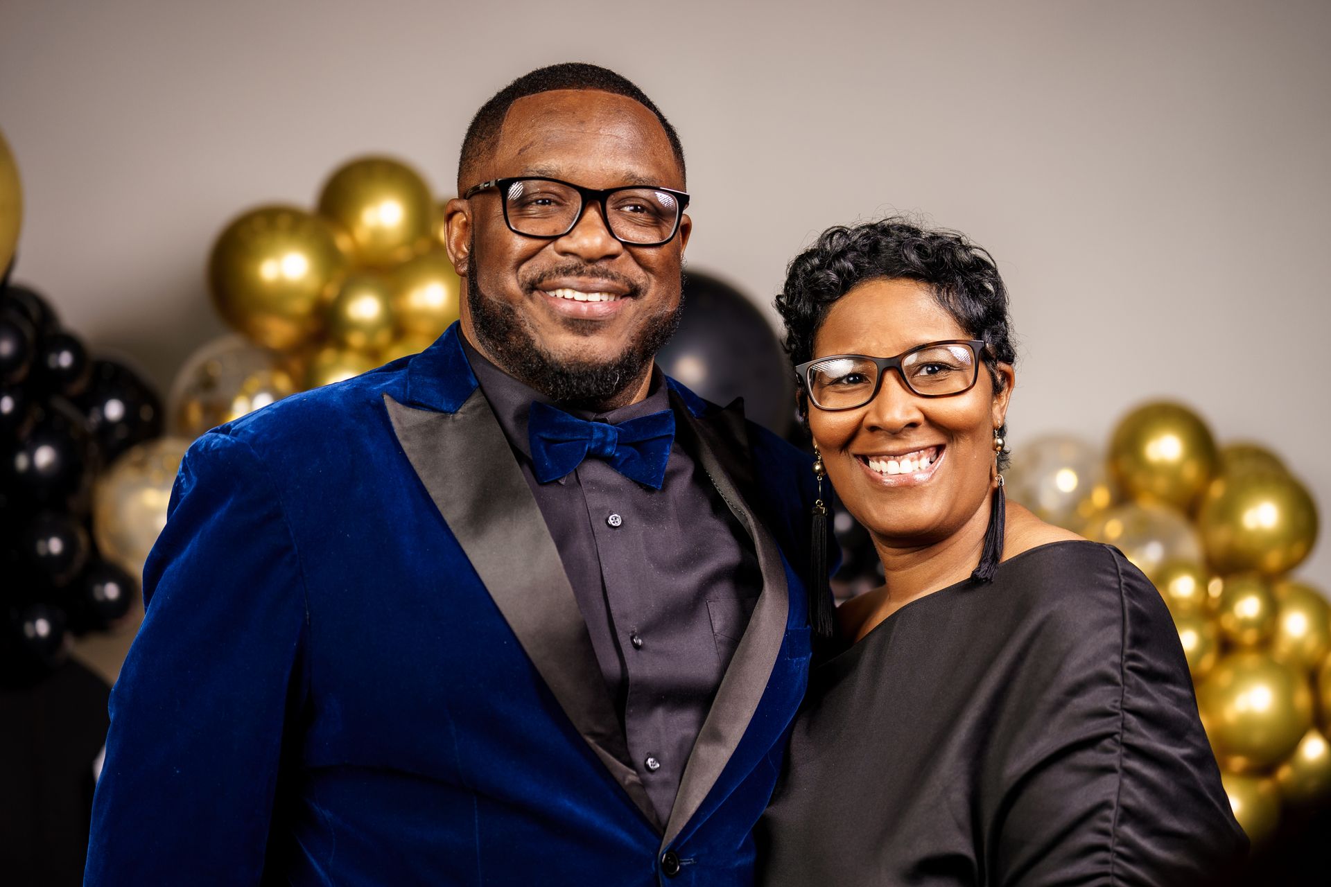 A man and a woman are posing for a picture in front of balloons.