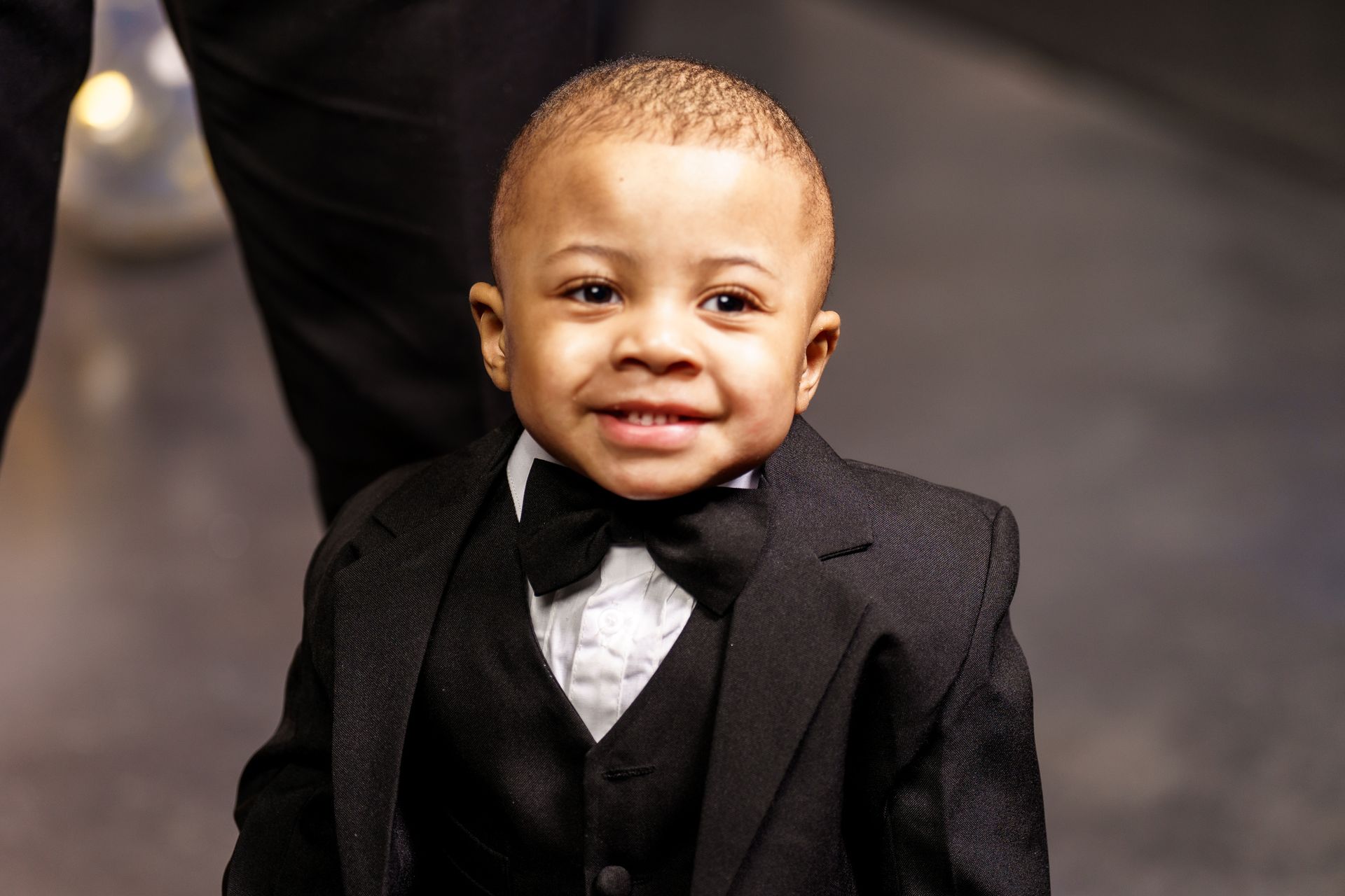 A little boy is wearing a tuxedo and bow tie.