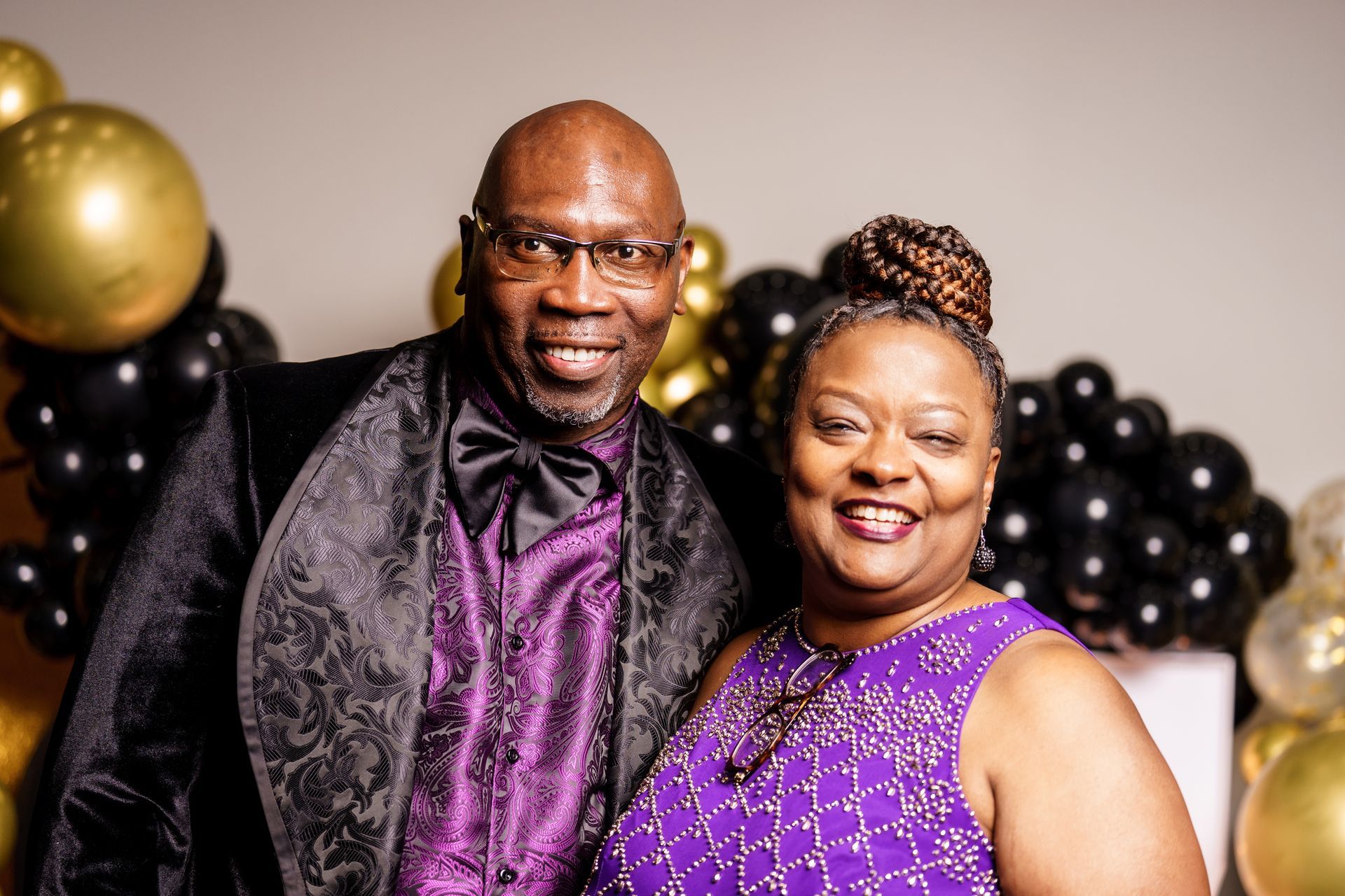 A man and a woman are posing for a picture in front of balloons.