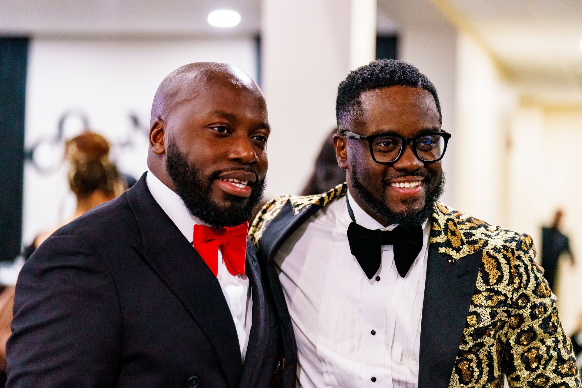 Two men in suits and bow ties are posing for a picture.