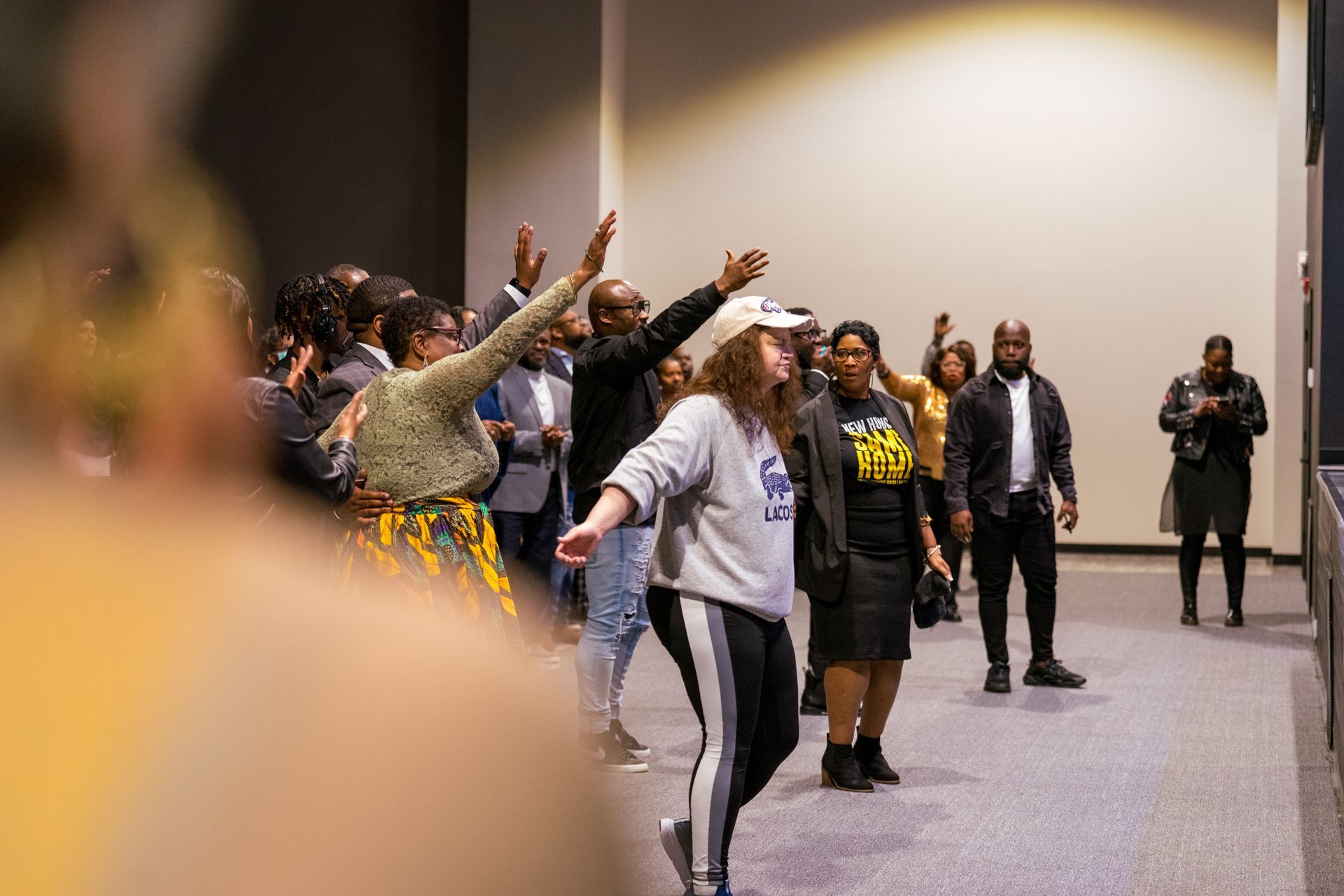 A group of people are dancing in a room with their hands in the air.