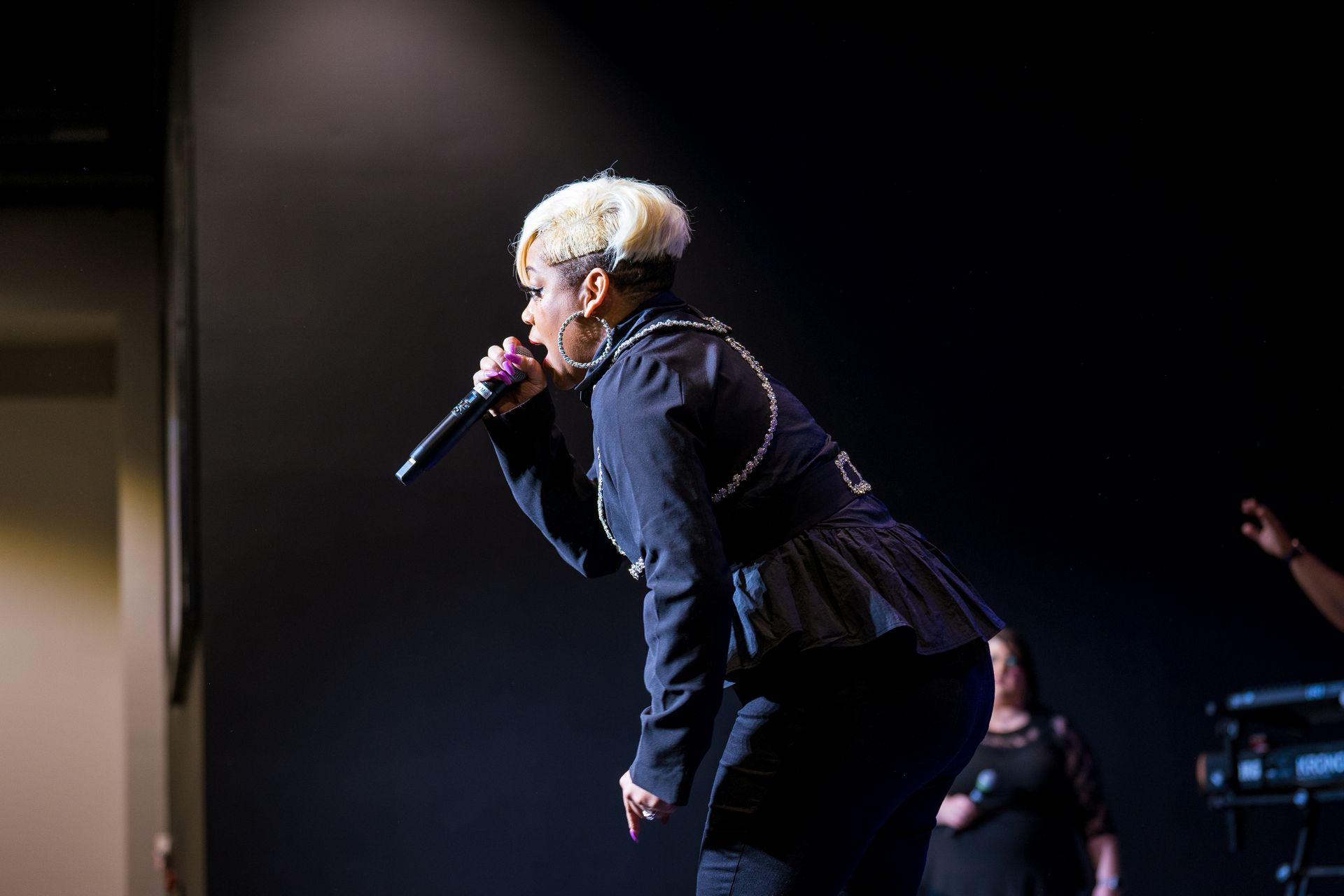 A woman is singing into a microphone on a stage.