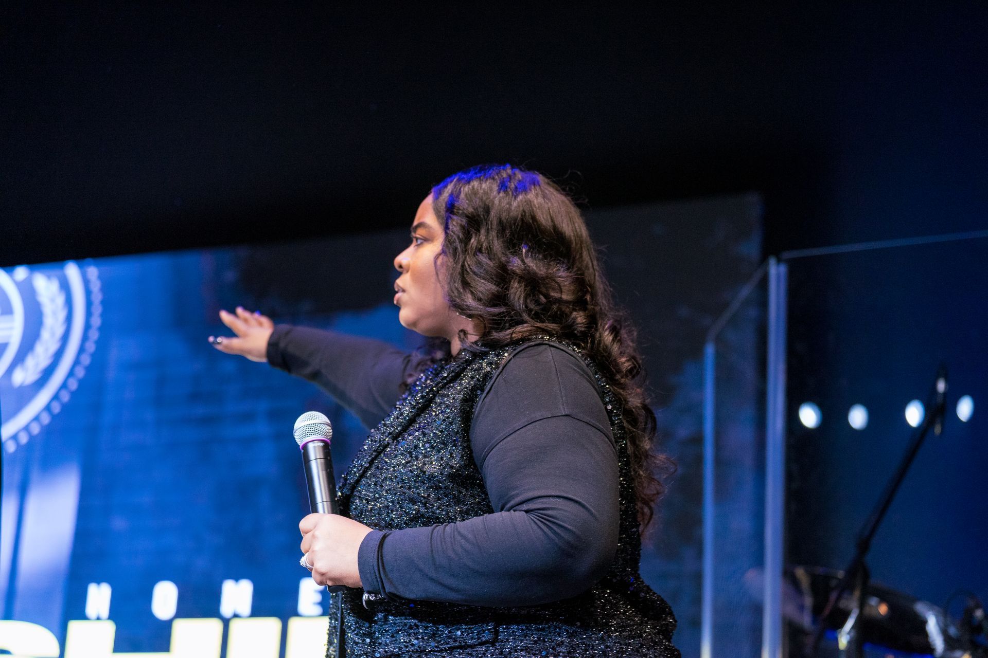 A woman is singing into a microphone on a stage.