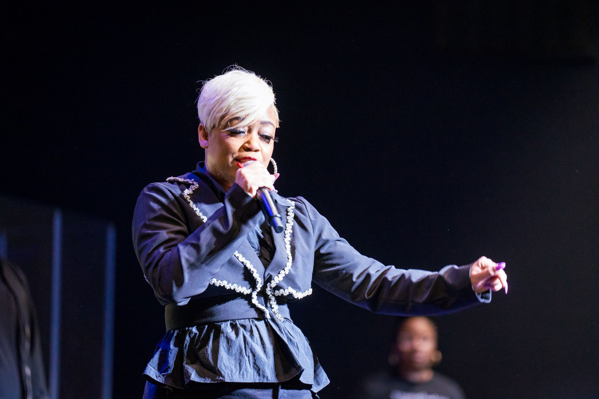 A woman is singing into a microphone on a stage.