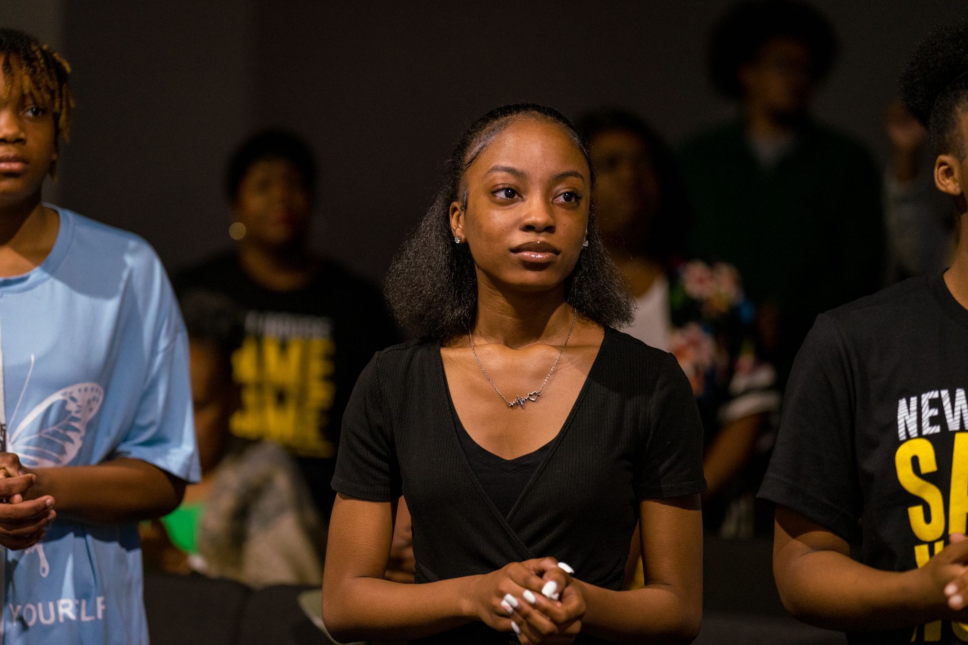 A group of young people are standing in a dark room.
