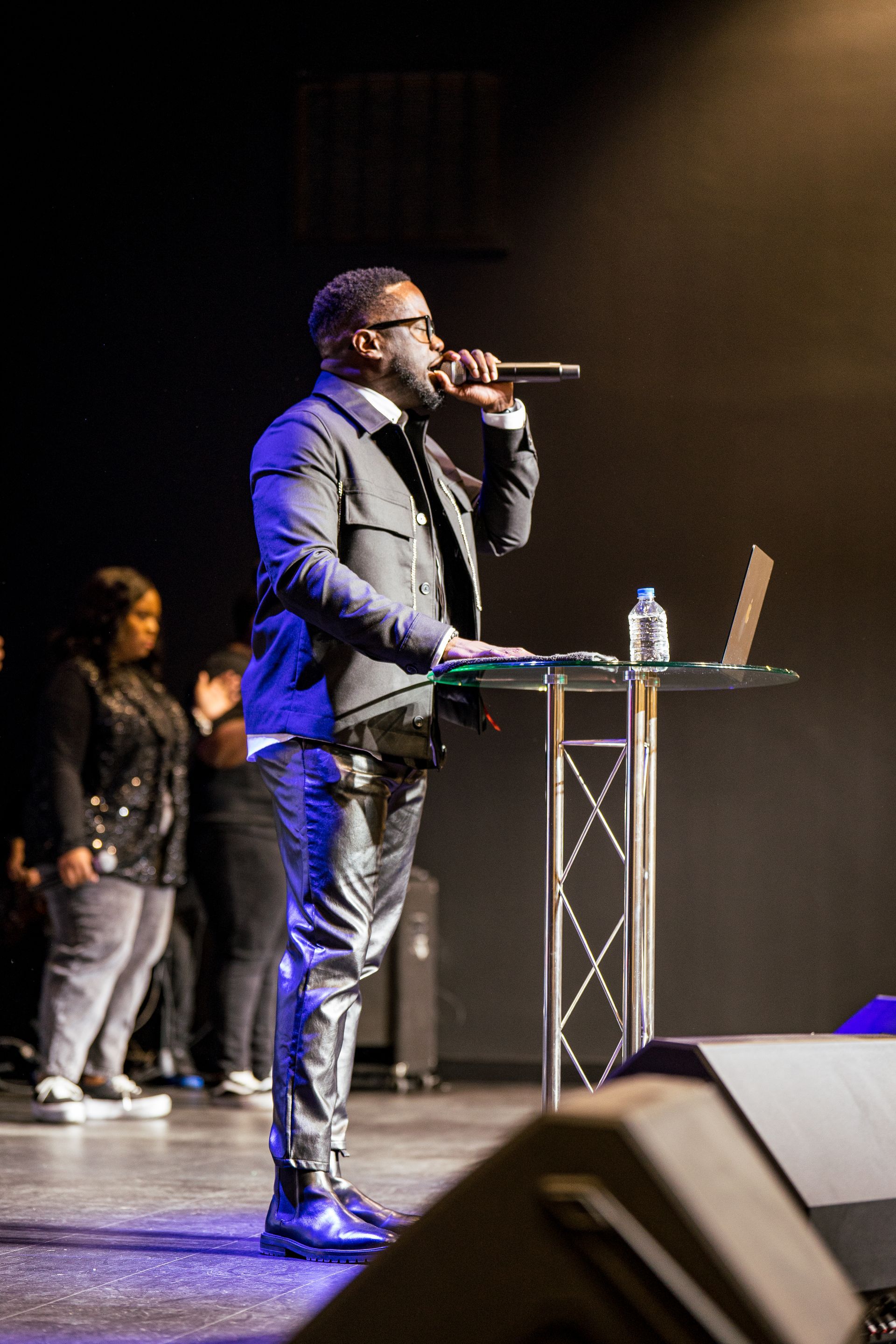 A man in a suit is singing into a microphone on a stage.