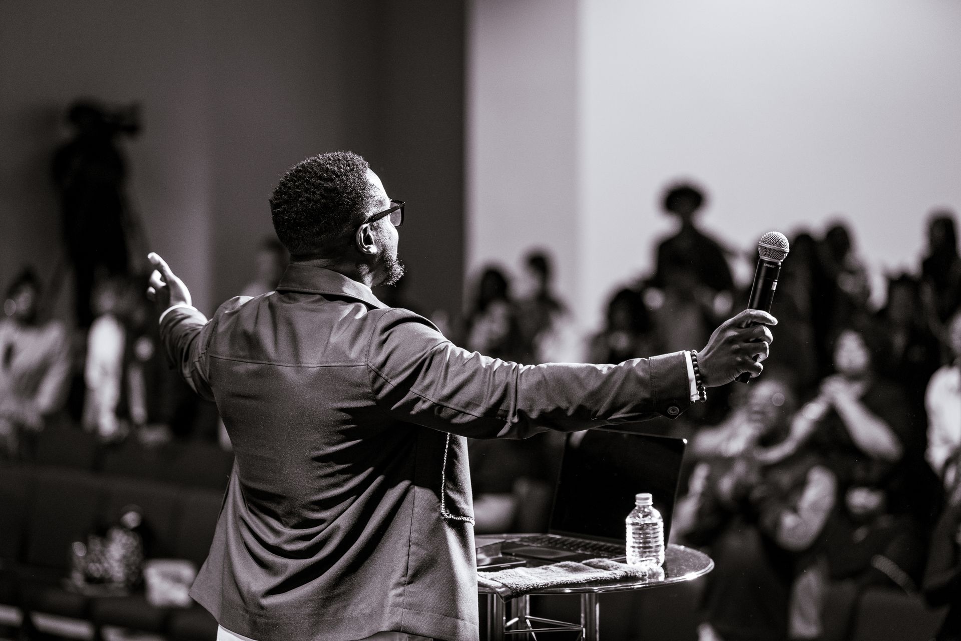 A man is standing at a podium holding a microphone in front of a crowd.