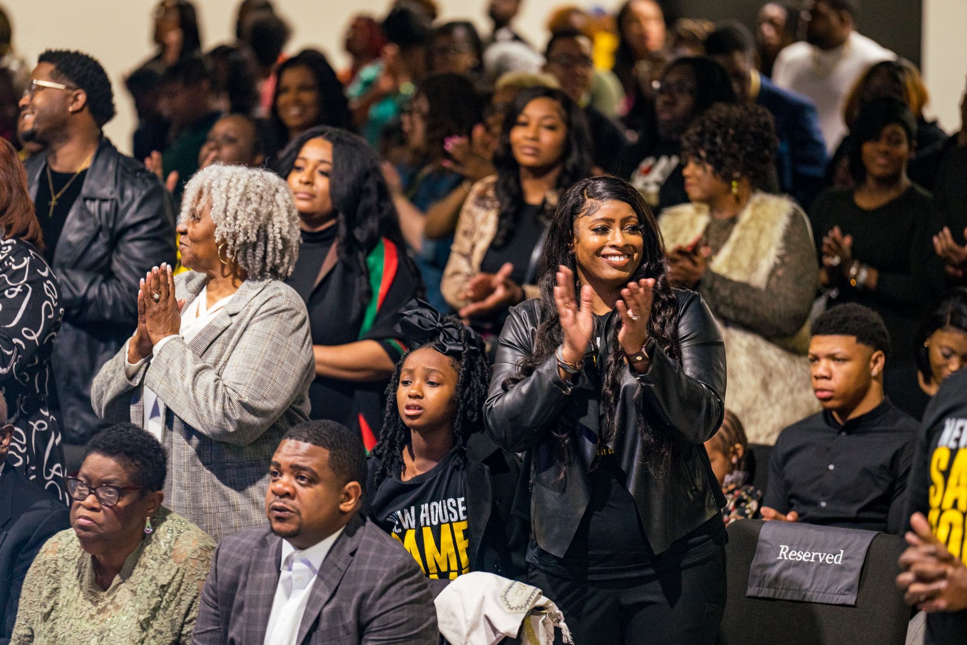 A large group of people are sitting in a stadium applauding.