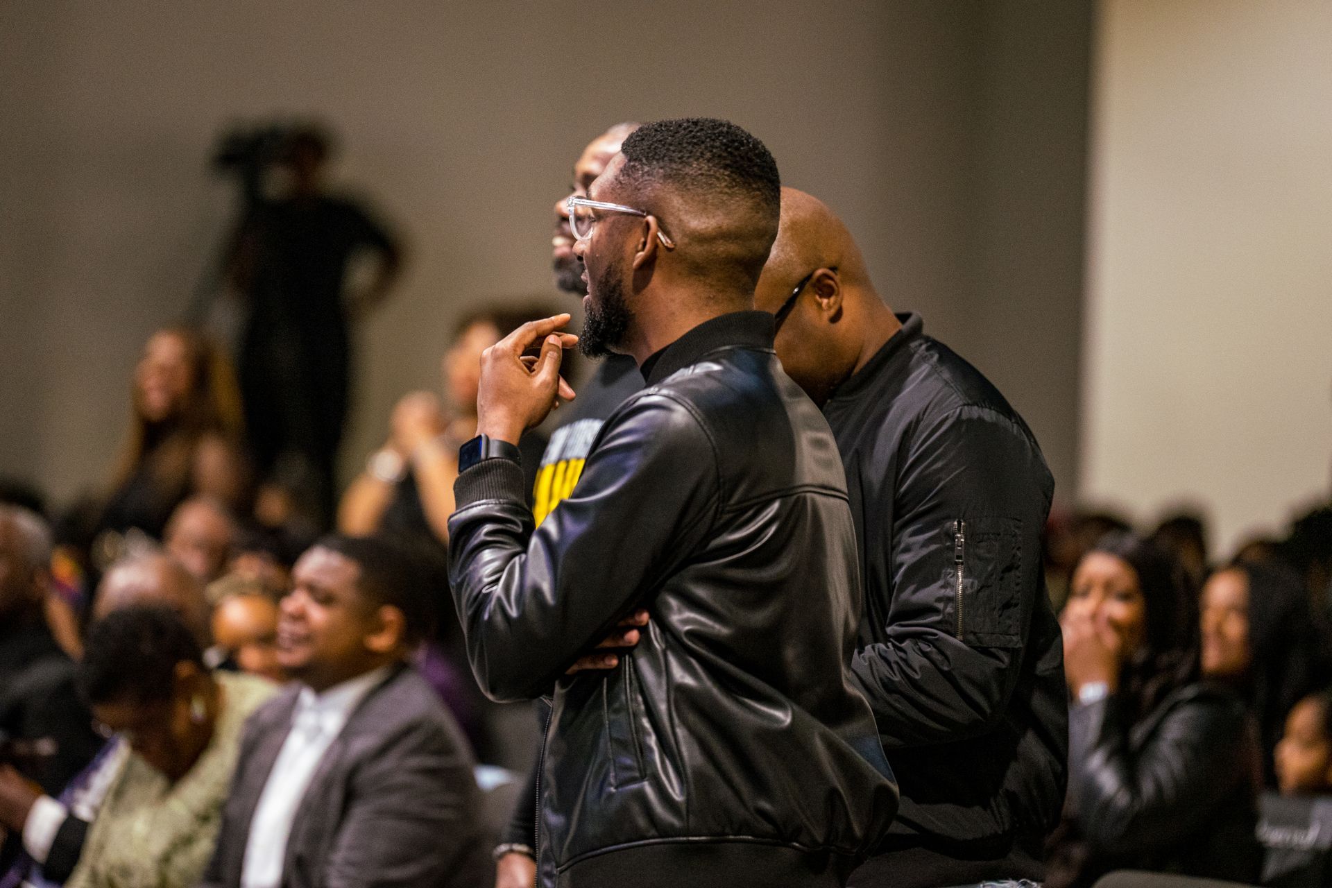 Two men are standing next to each other in front of a crowd of people.