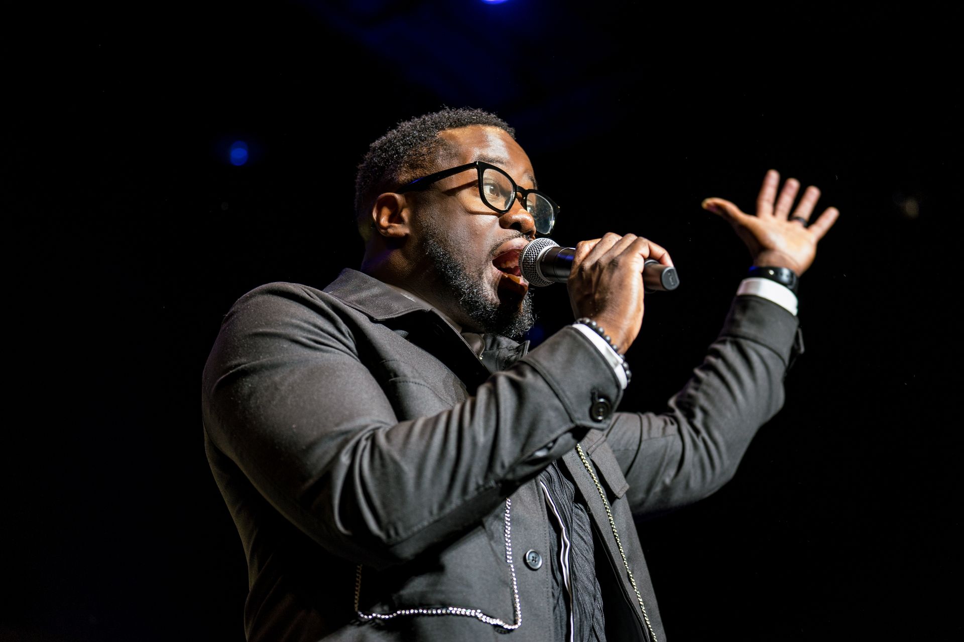 A man in a suit is singing into a microphone on a stage.